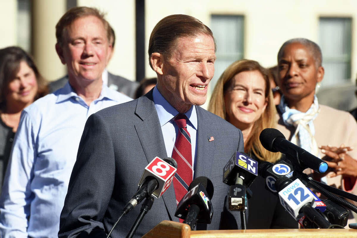 Richard Blumenthal Talking Into A Bunch Of Microphones Background