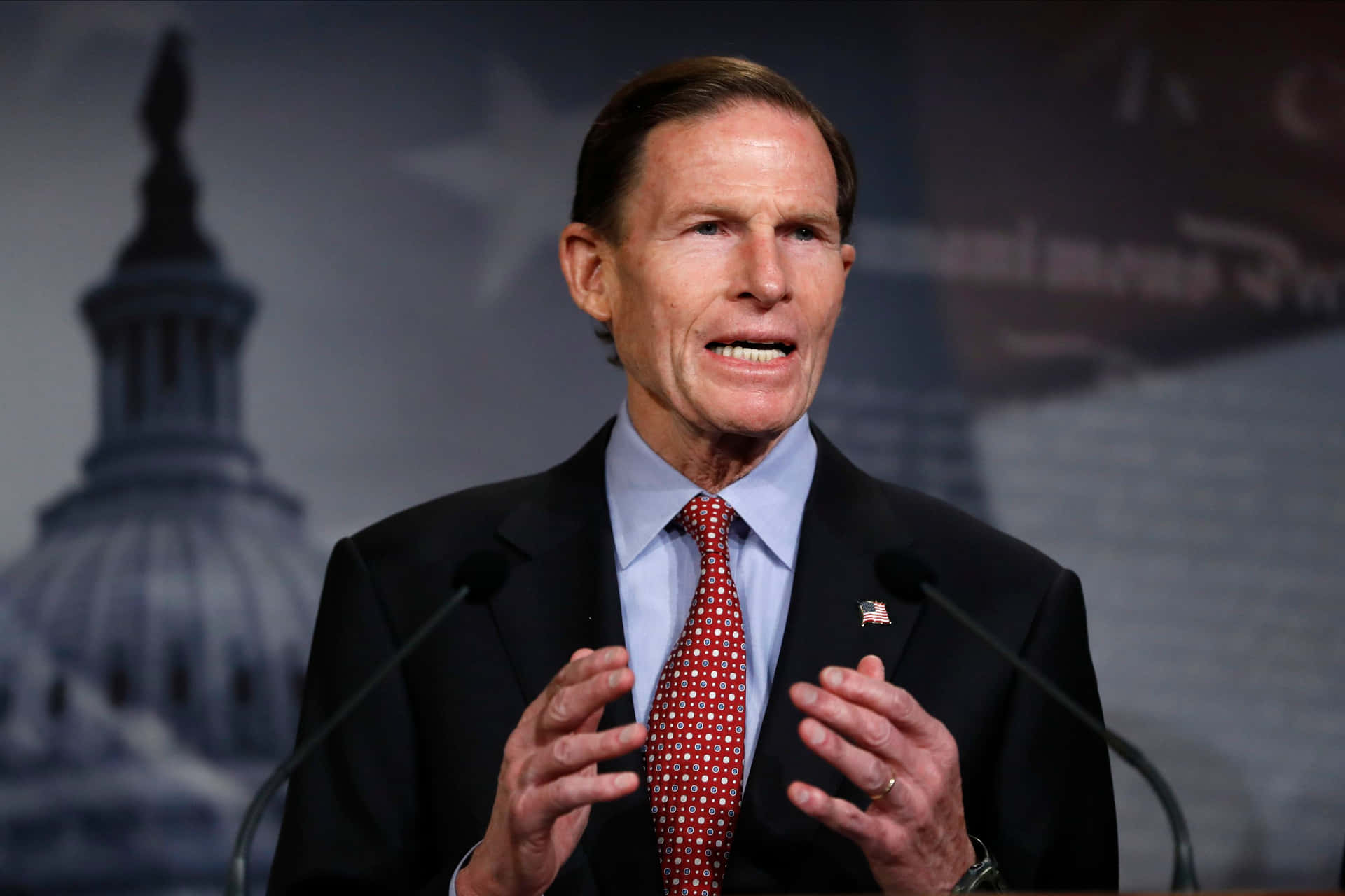 Richard Blumenthal With Gray Backdrop Of American Imagery
