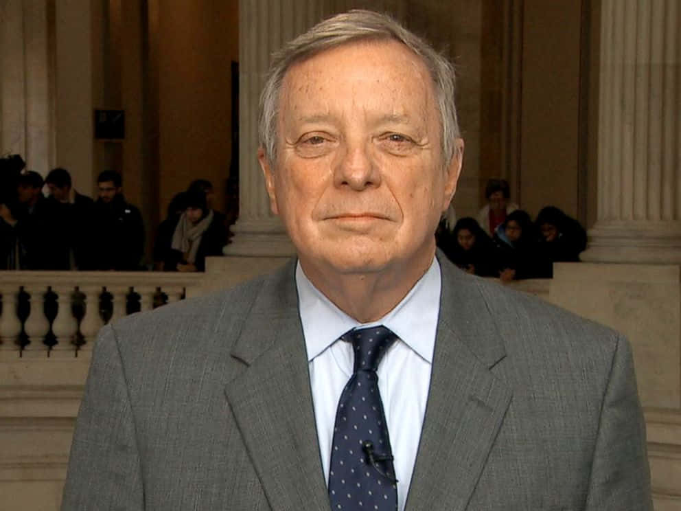 Richard Durbin Smiling At A Conference Background