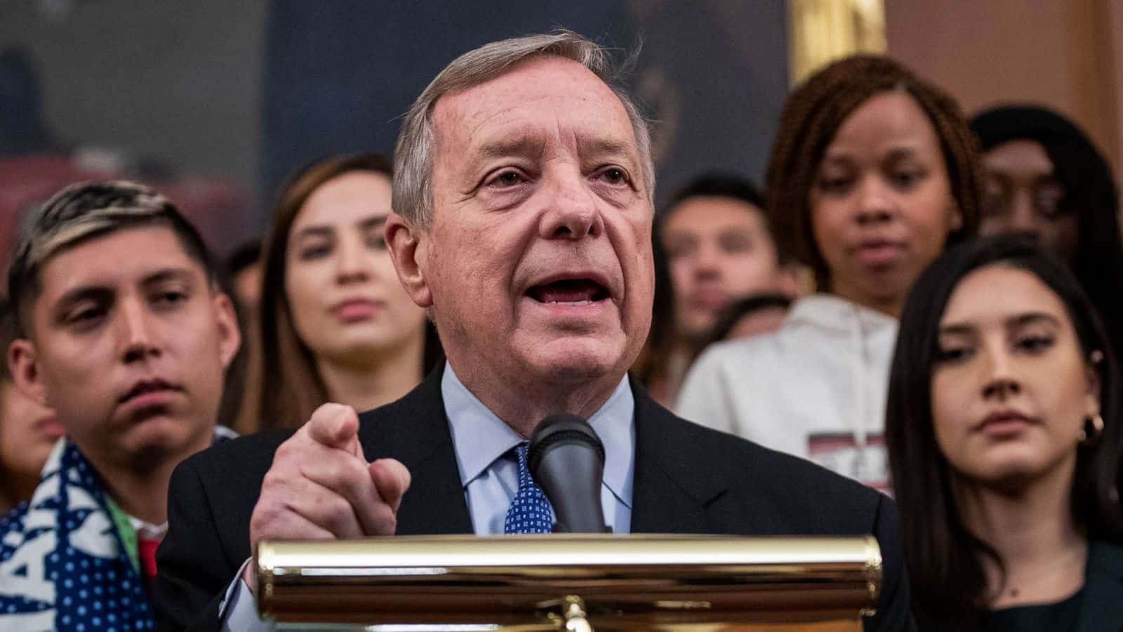 Richard Durbin Speaking At Podium Background