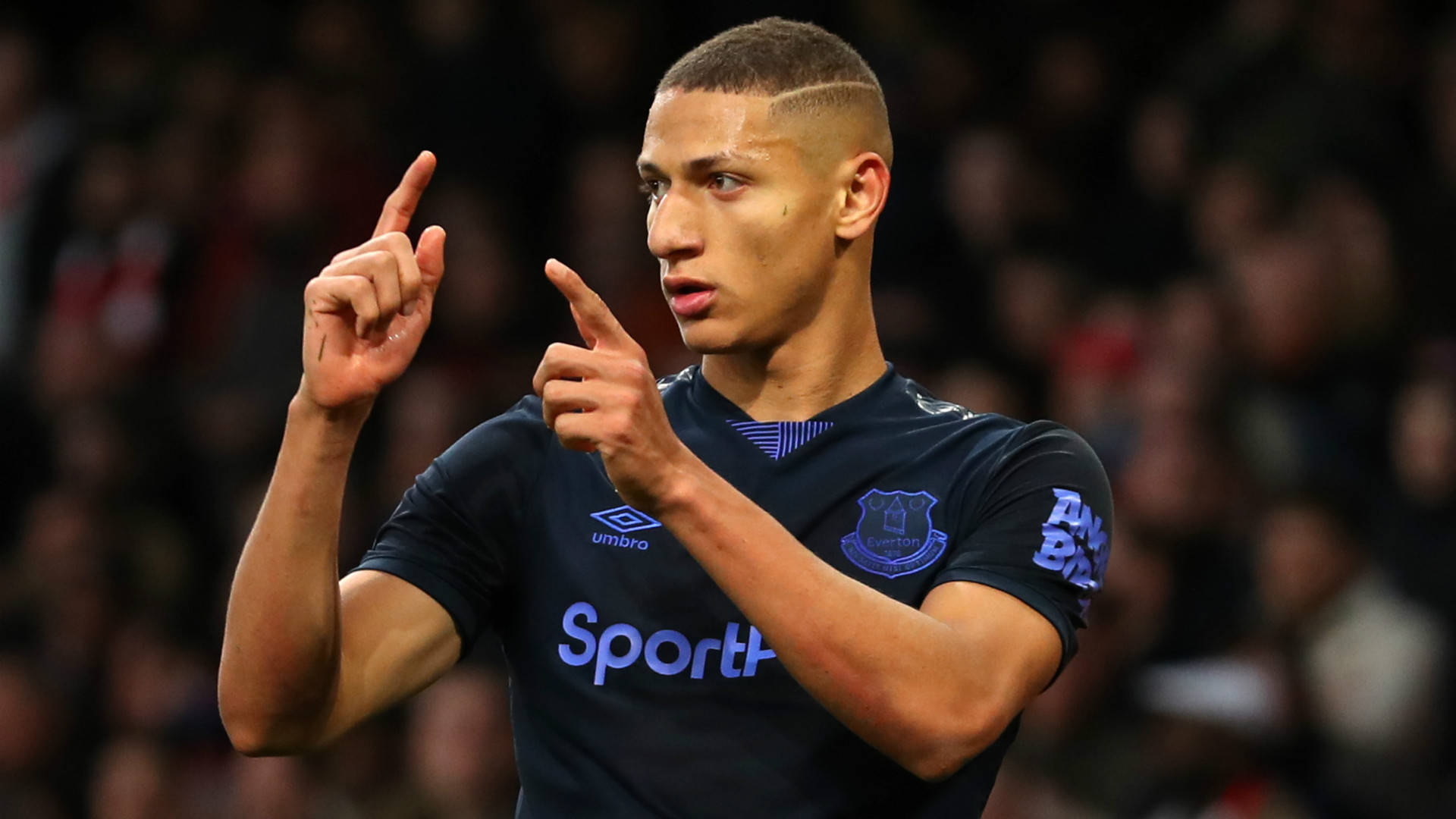 Richarlison De Andrade Performing His Iconic Finger Gun Celebration On The Soccer Field Background