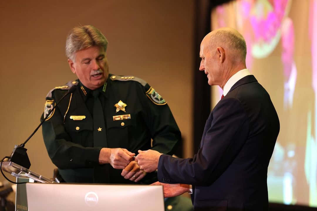 Rick Scott And A Police Officer Background