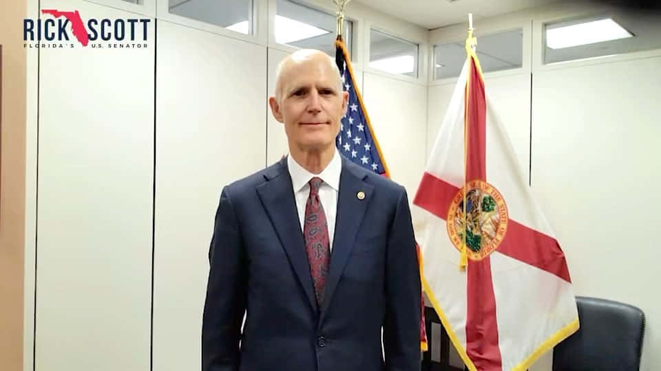 Rick Scott Poses With Flags On Background Background