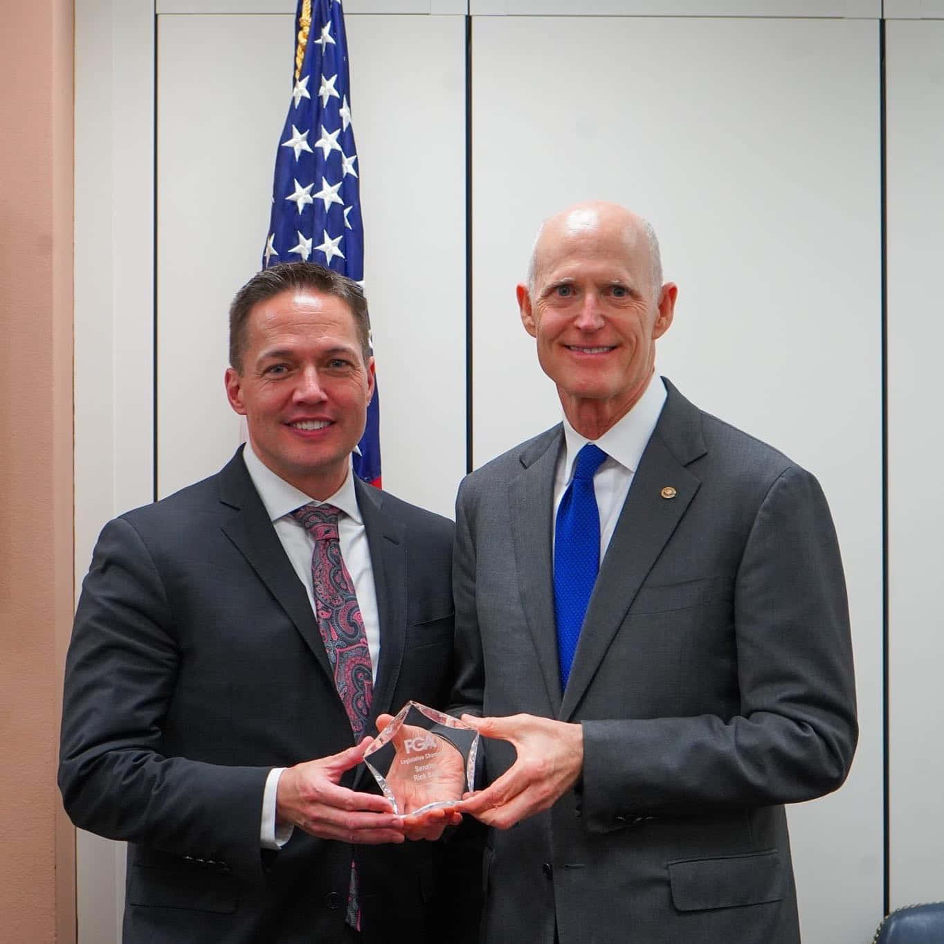 Rick Scott Proudly Holding A Trophy Award Background