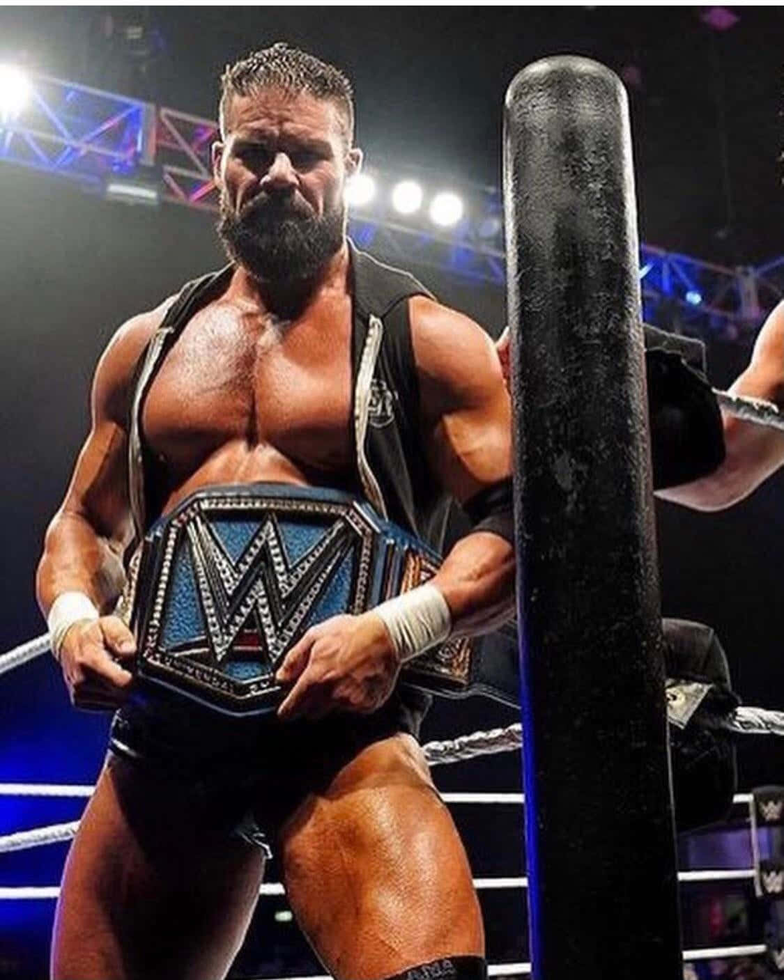 Robert Roode Proudly Holding His Championship Belt With A Big 'w'-letter Background