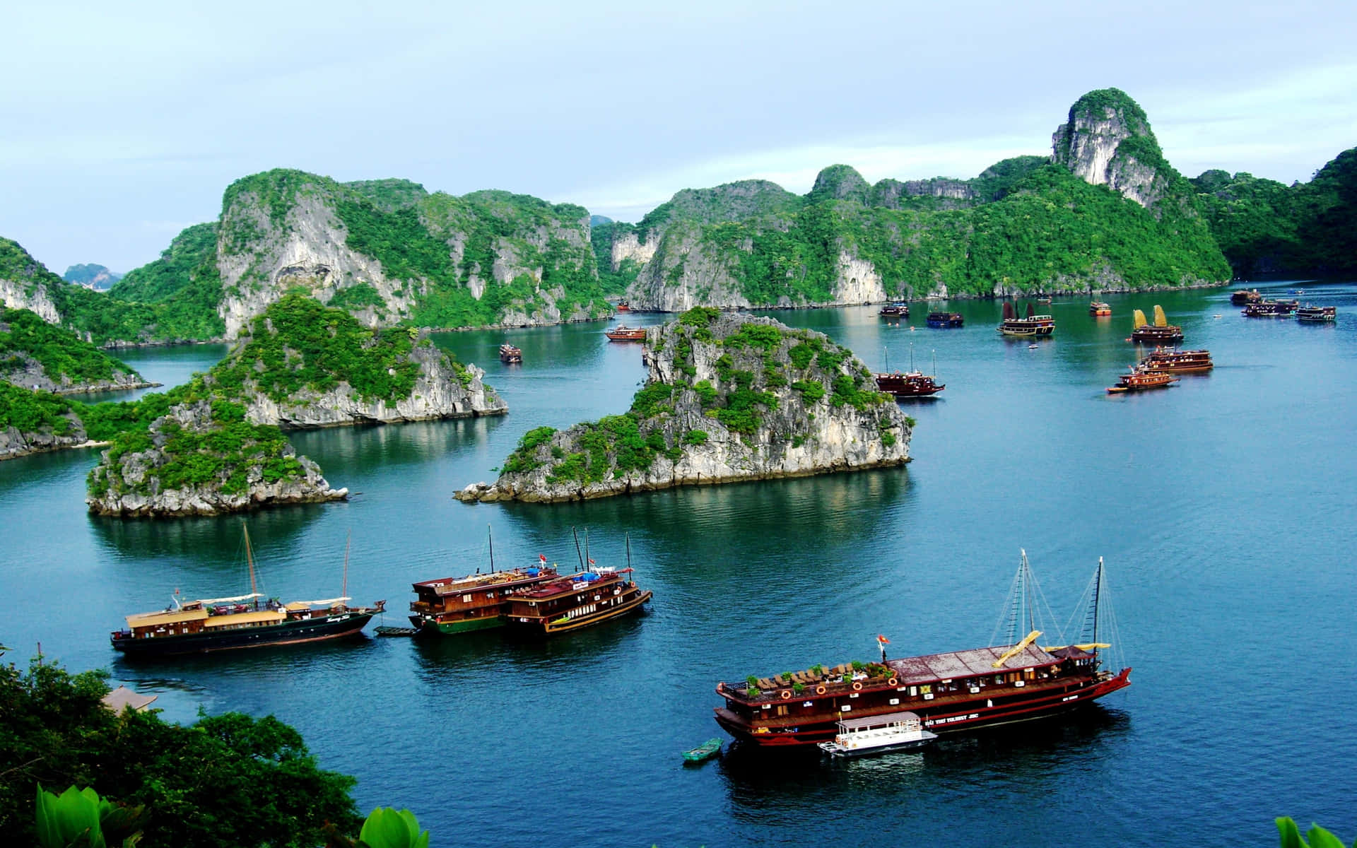 Rock Formations And Ships In Halong Bay Background