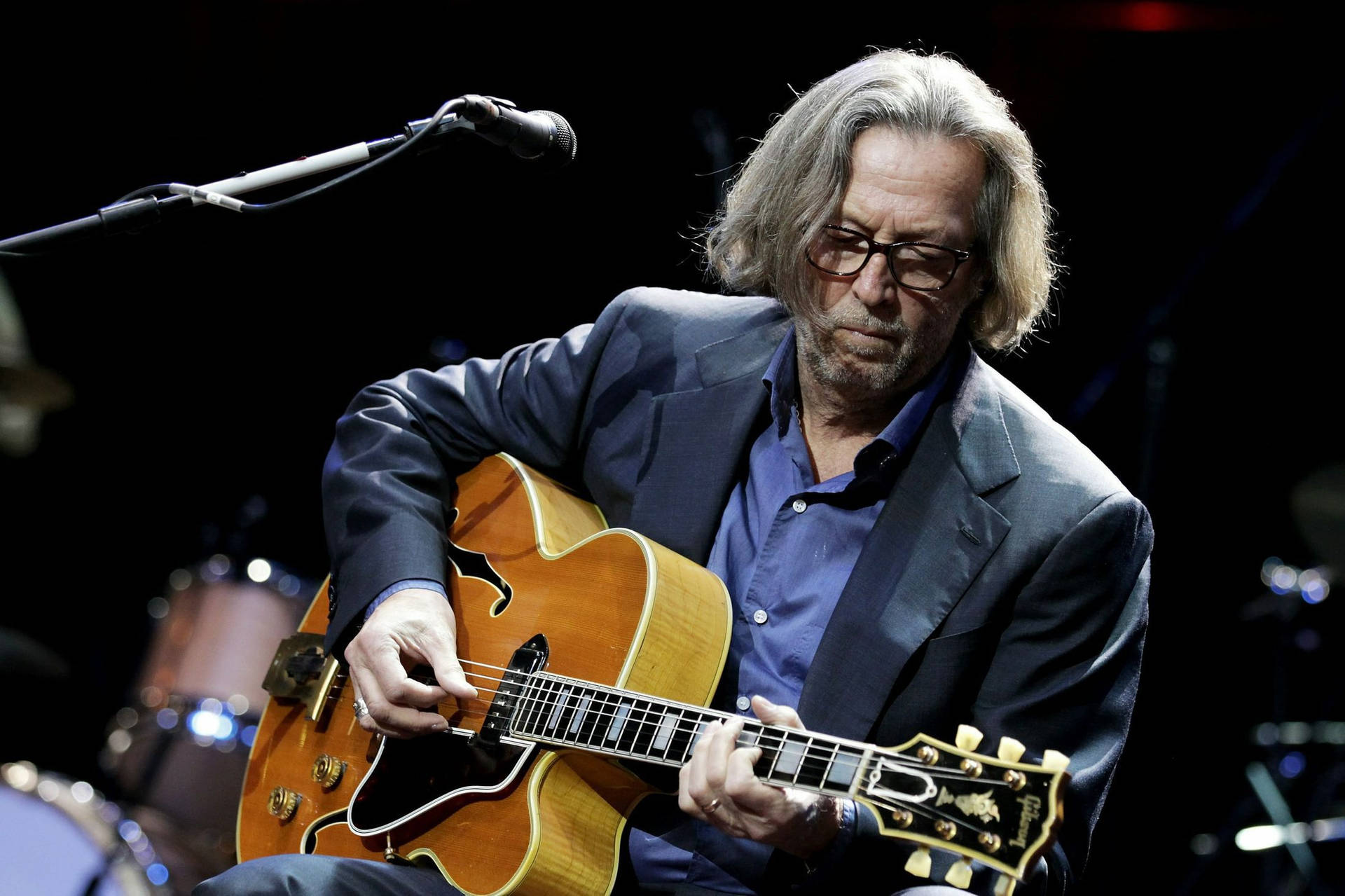 Rock Legend Eric Clapton Engrossed In Playing Acoustic Guitar Background