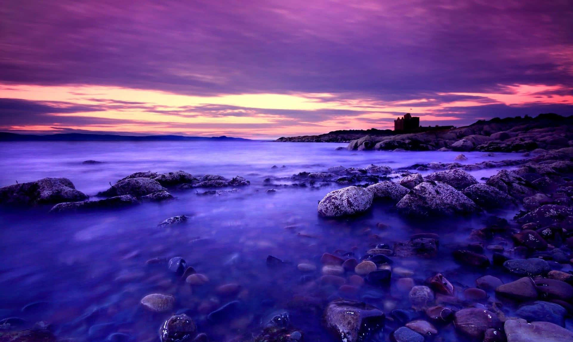 Rocky Shore With A Blue And Purple Sunset Background