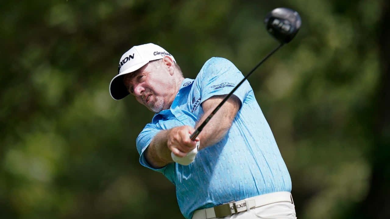 Rod Pampling Delivers A Powerful Swing In Blue Shirt Background