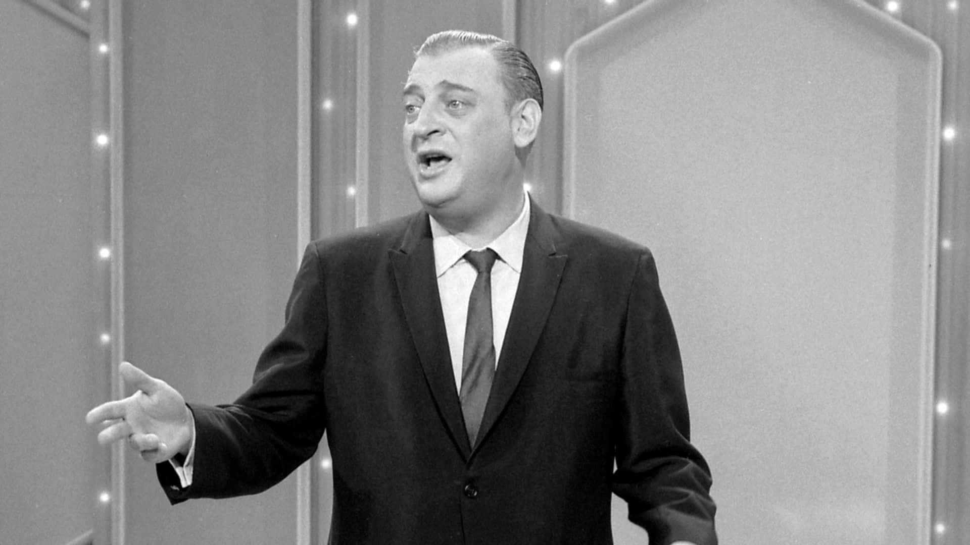 Rodney Dangerfield Gracing The Stage In Quintessential Monochrome Background
