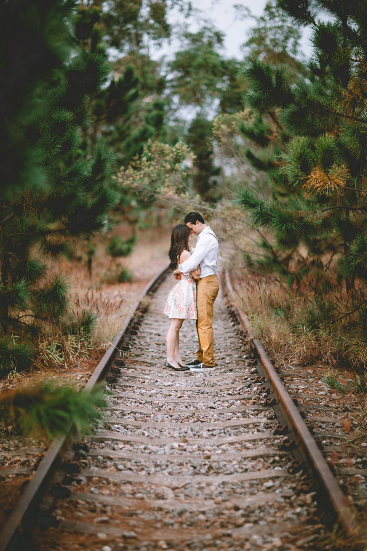Romantic Couple Embrace On Train Tracks Background
