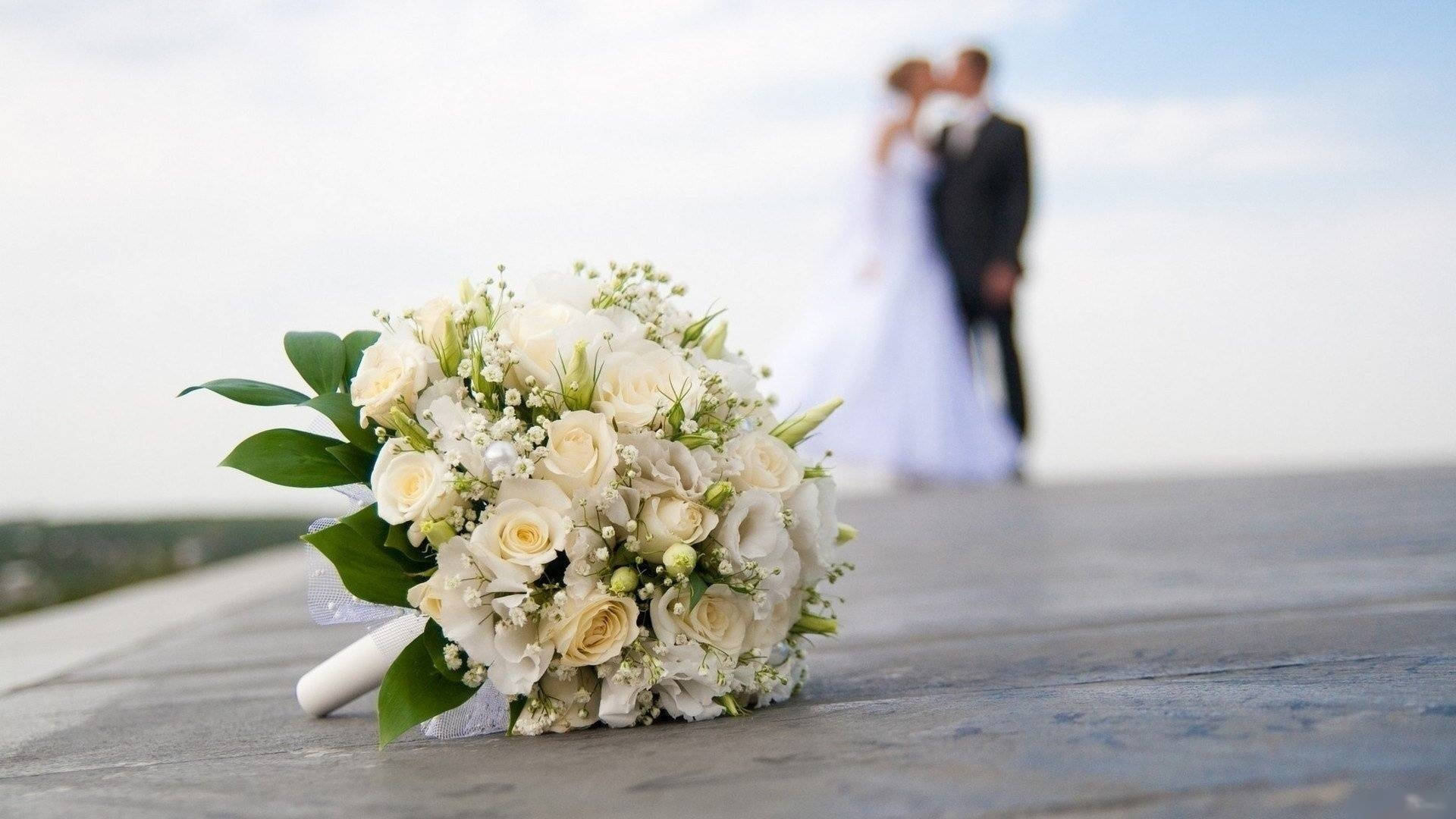 Romantic Couple Sharing A Kiss Behind A Vibrant Wedding Bouquet. Background