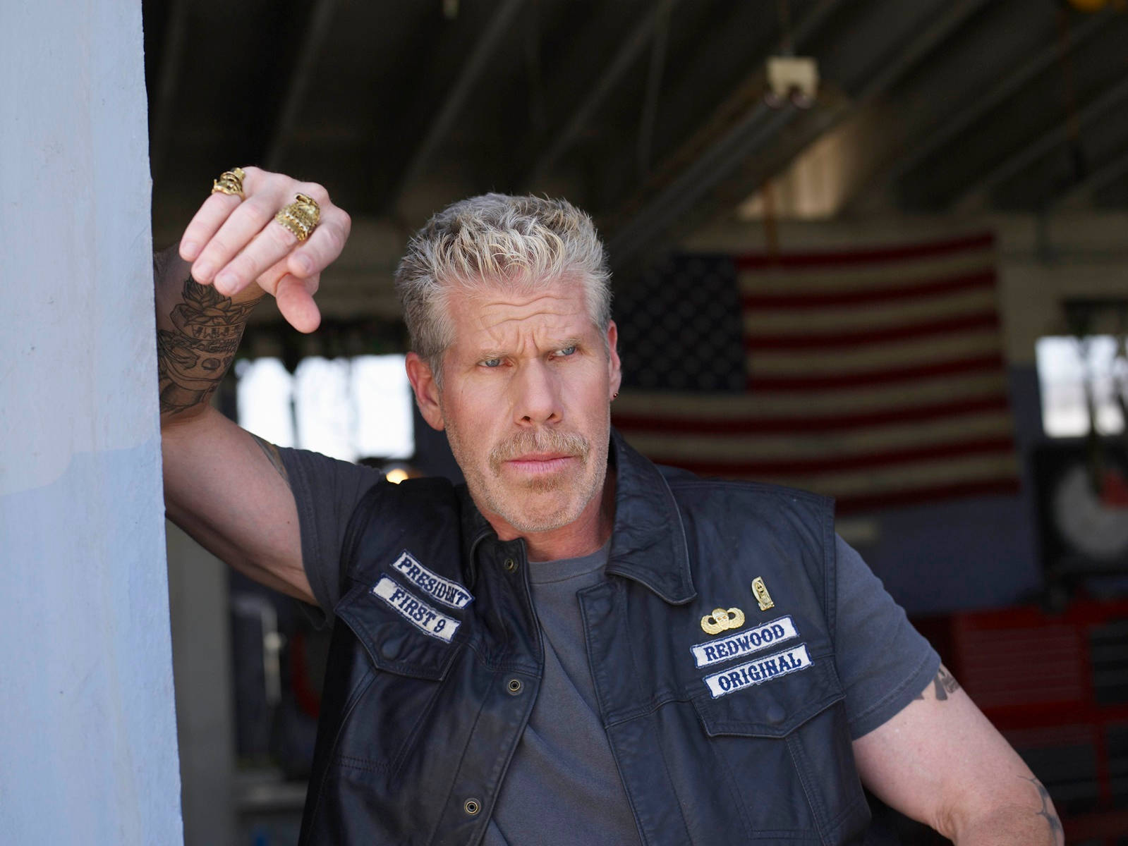 Ron Perlman's Arm Leaning On A Wall Background