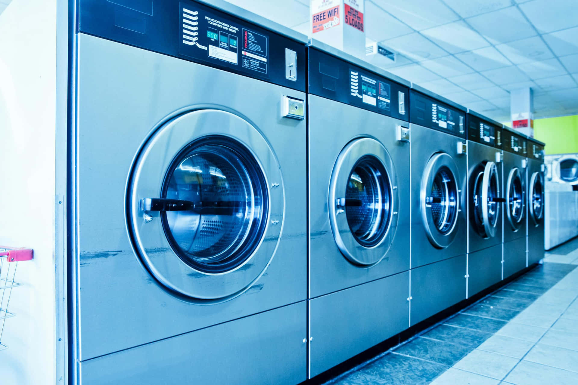 Rowof Industrial Washing Machinesin Laundromat Background