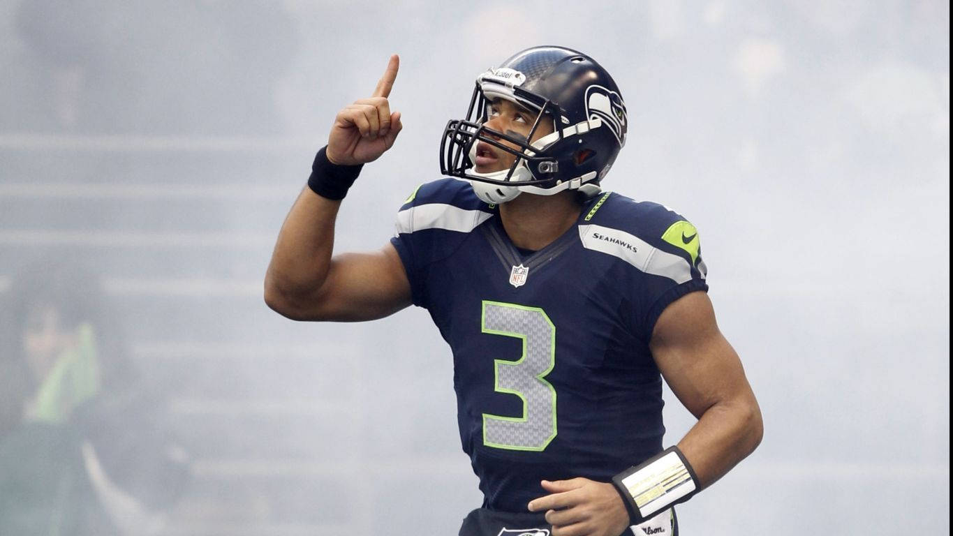 Russell Wilson Pointing Up Surrounded By Fog Background