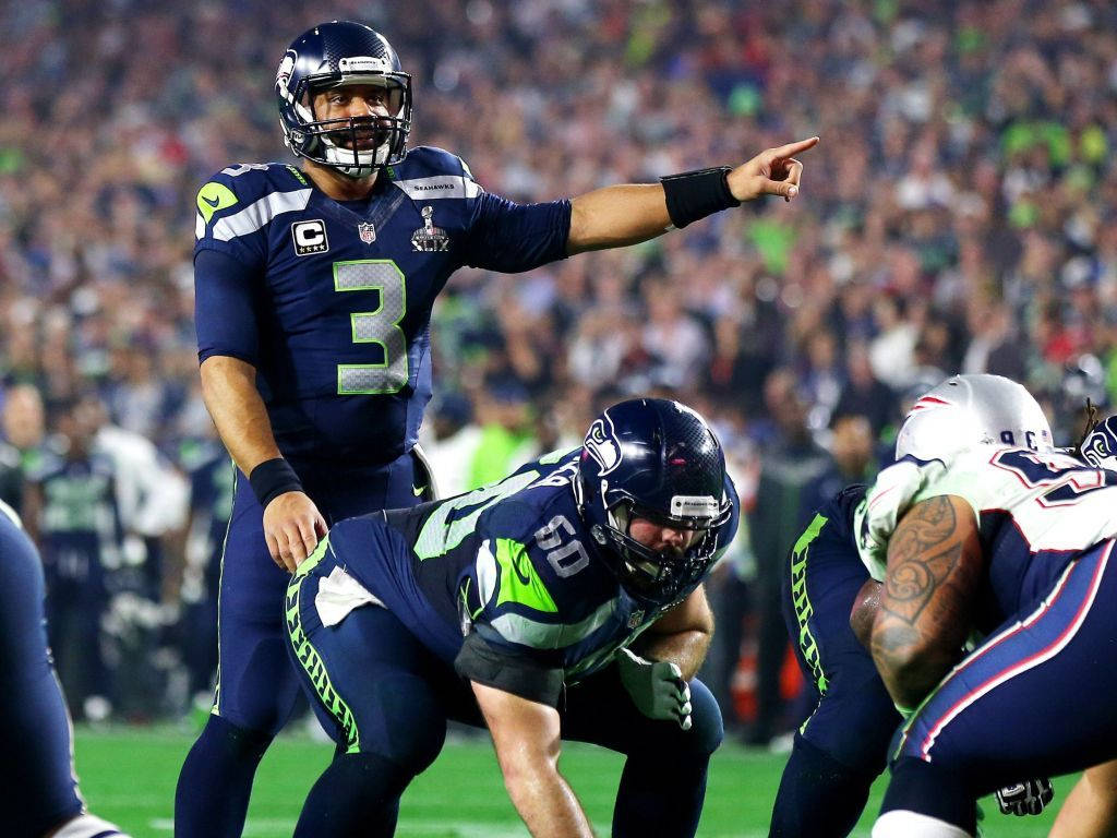 Russell Wilson Pointing While Team Is Crouching Background