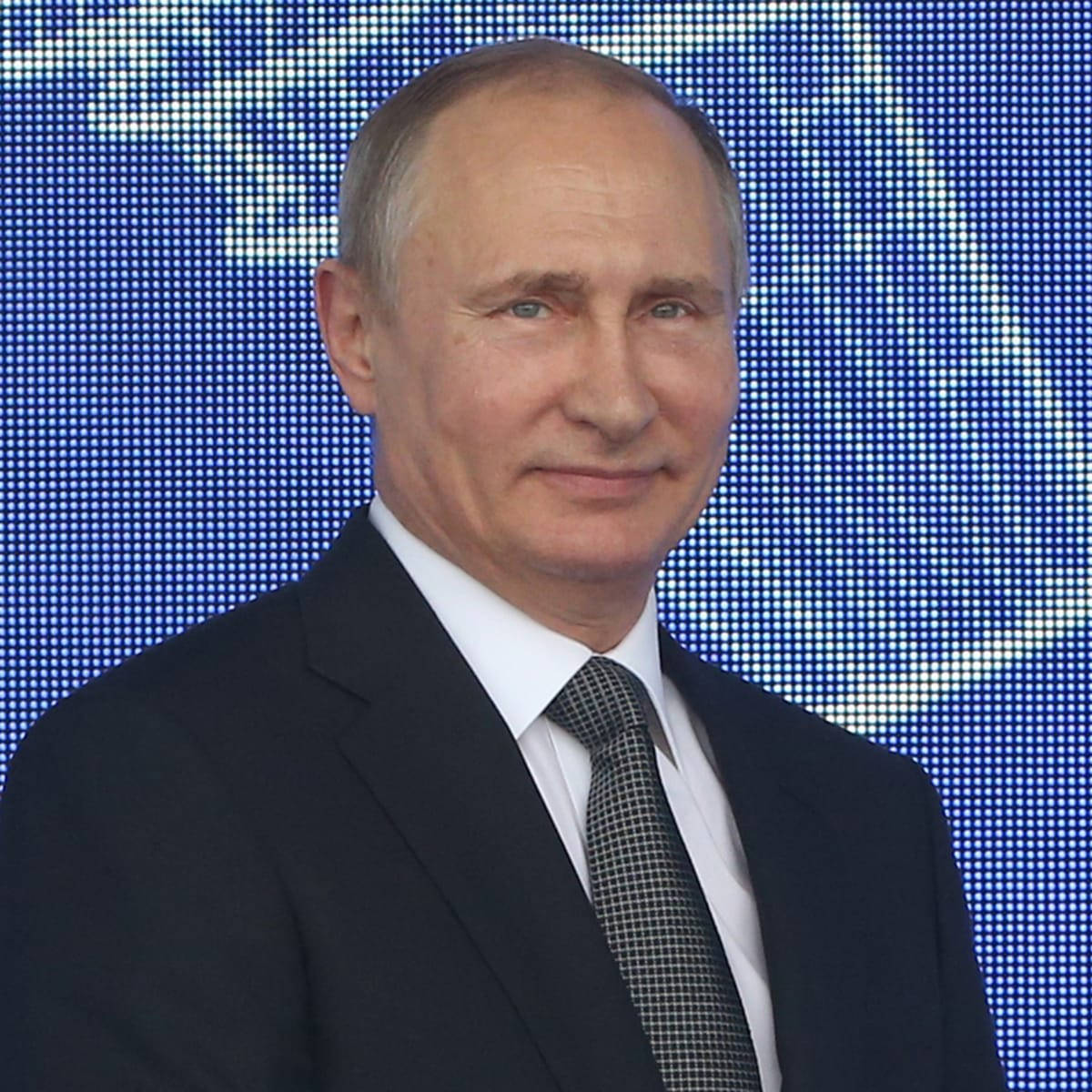 Russian President Vladimir Putin Smiling Against A Blue Background Background