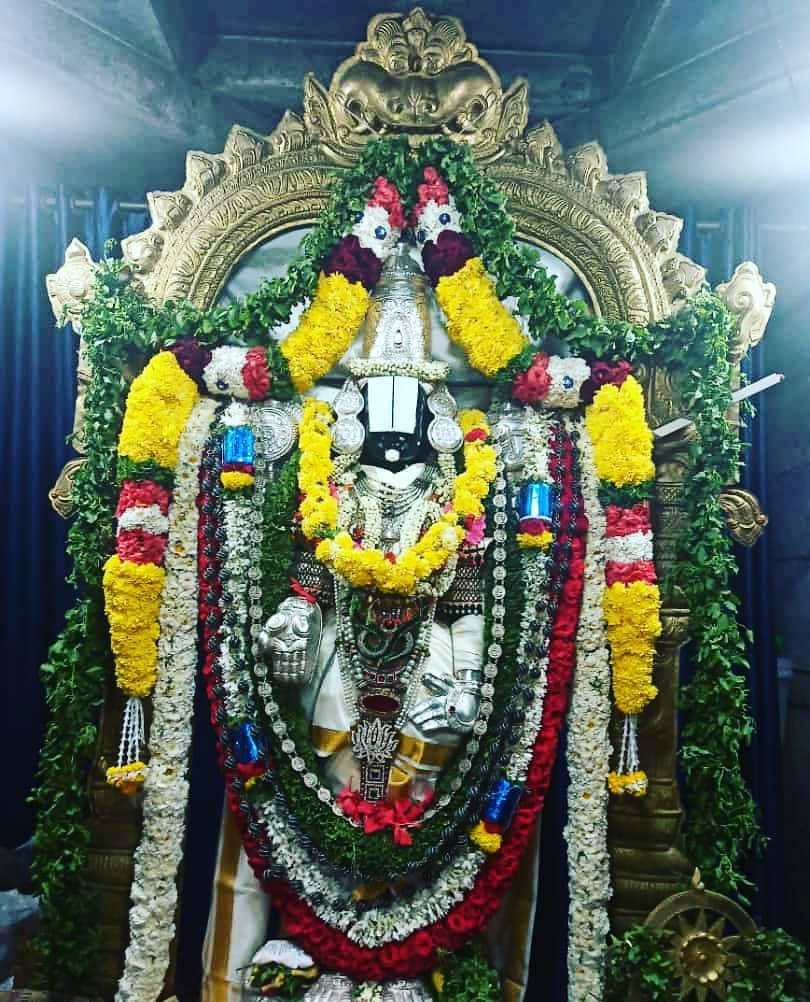 Sacred Statue Of Lord Venkateswara Adorned With Floral Garlands Background