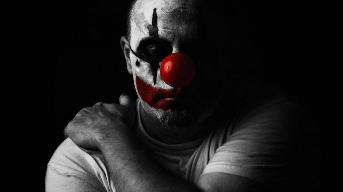 Sad Joker Clown Holding His Shoulder Background