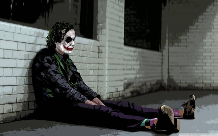 Sad Joker Sits Against The Wall Background