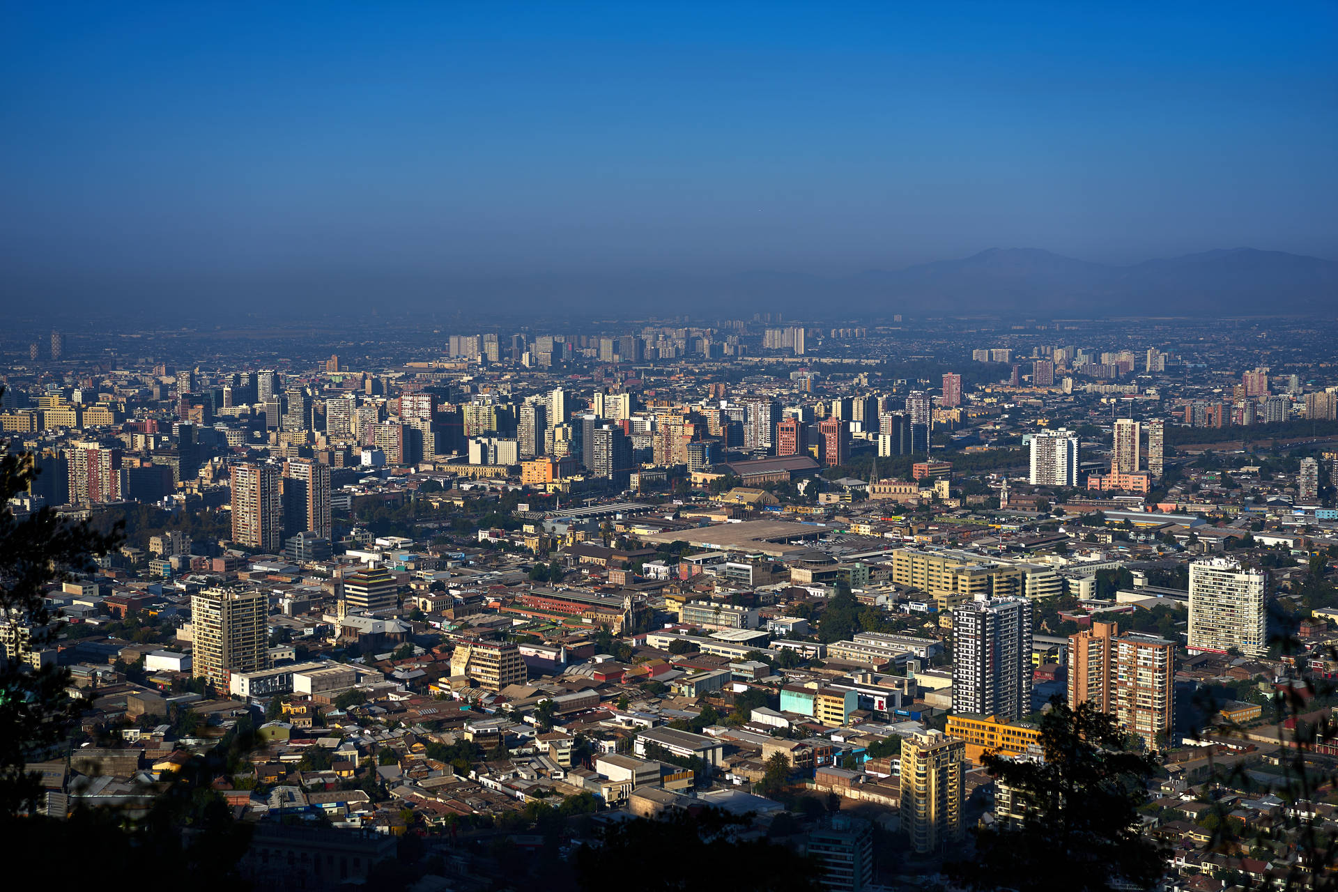 Santiago's Majestic Skyline Under A Blue Hazy Sky Background