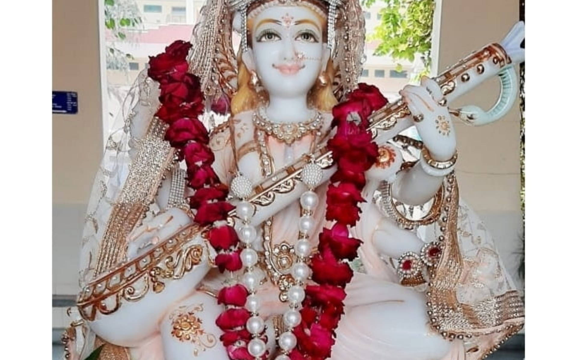 Saraswati White Statue Red Flowers Background