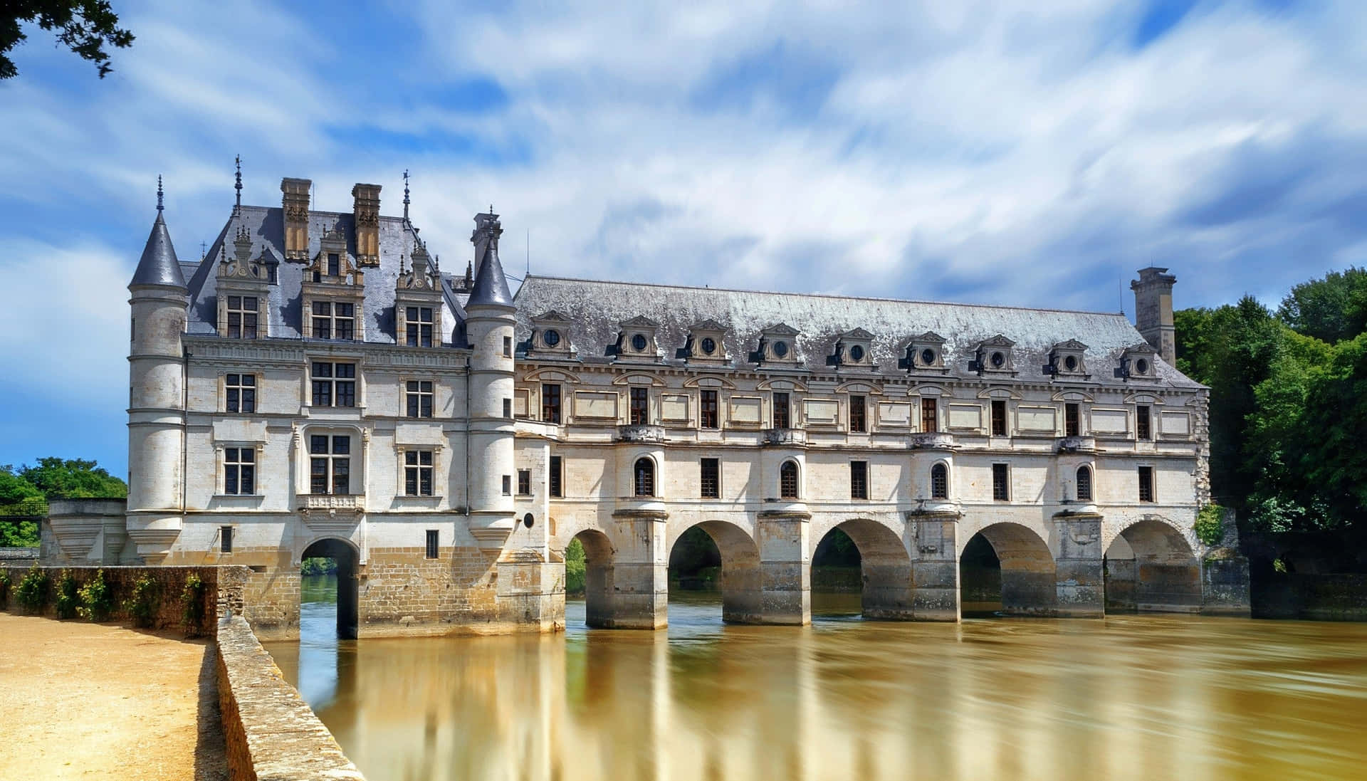 Scenic View Of Château De Chenonceau Over The Muddy River Background