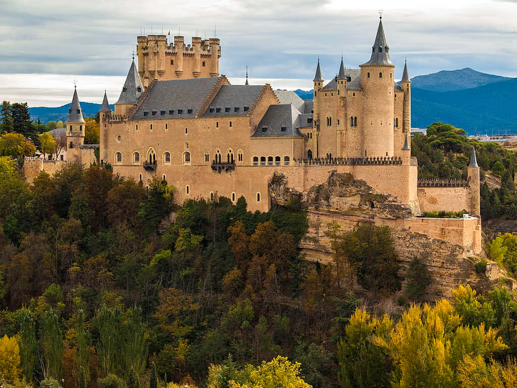 Segovia Castle Overlooking Trees And Mountains Background