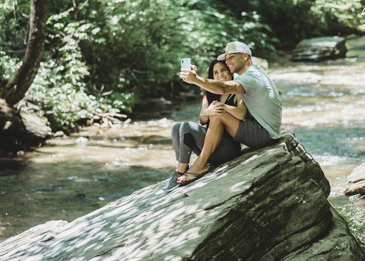 Selfie Man And Woman Near A River Background