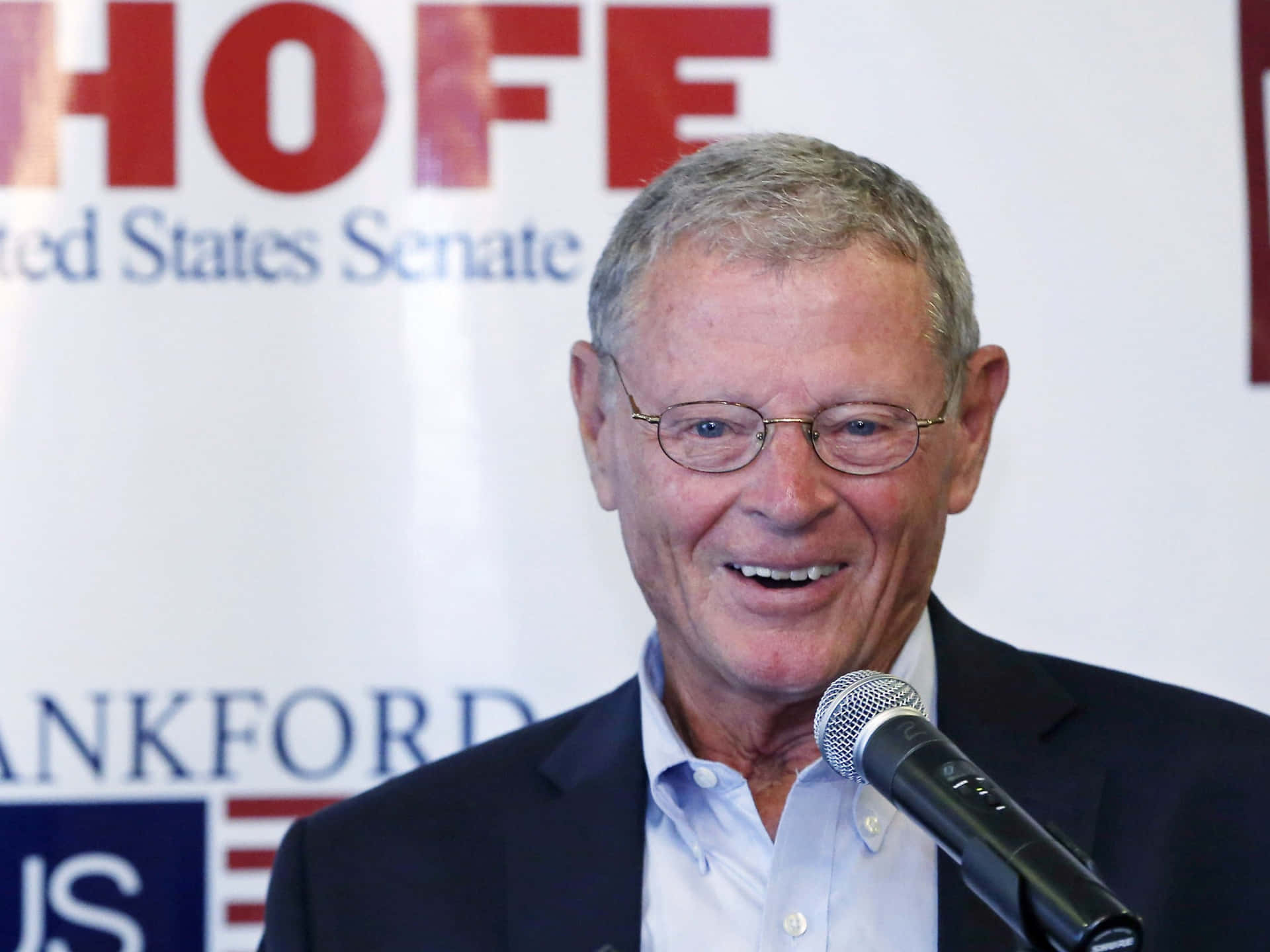 Senator Jim Inhofe Addressing The Media With A Microphone Background