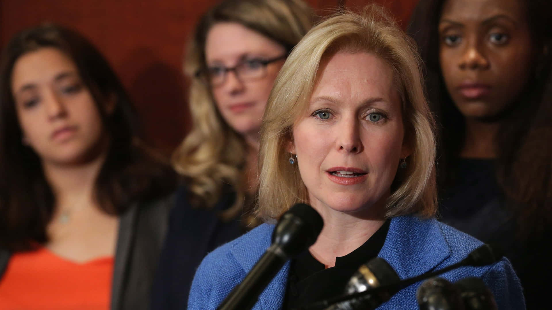 Senator Kirsten Gillibrand Addressing An Audience Of Women Background