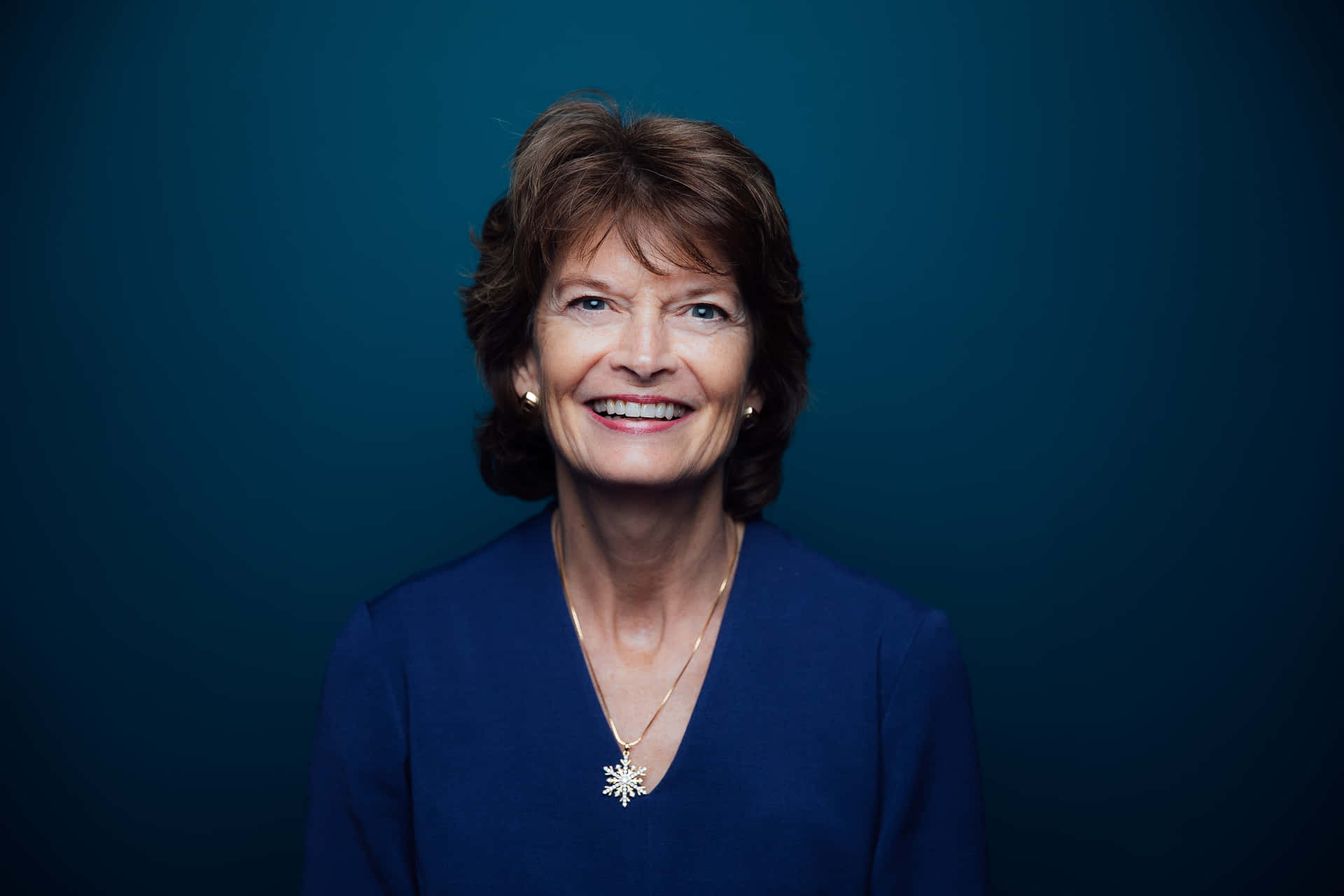 Senator Lisa Murkowski Smiling Against A Blue Aesthetic Background Background