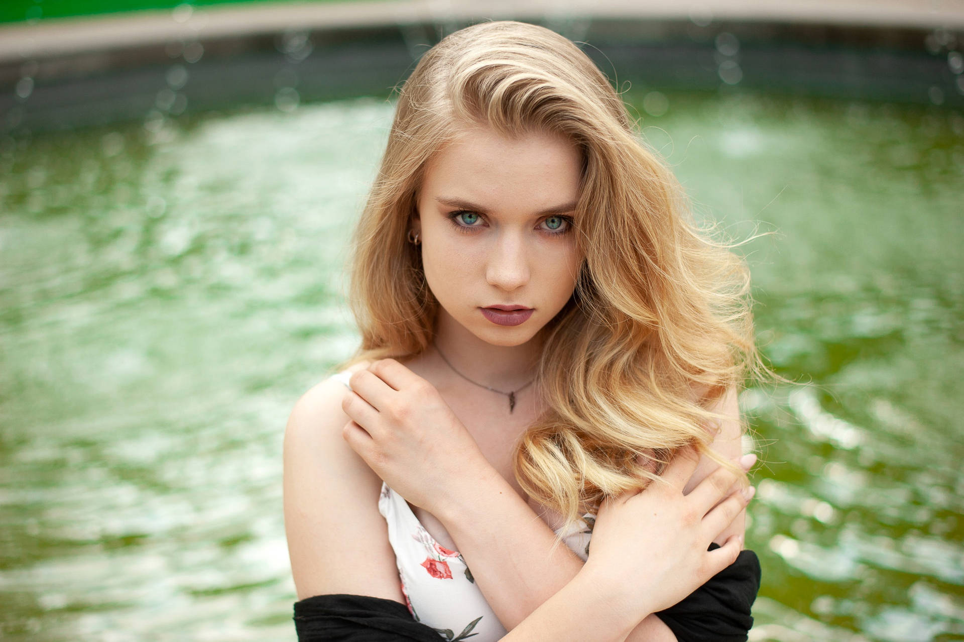 Serene Blonde Woman Enjoying A Moment By The Fountain Background