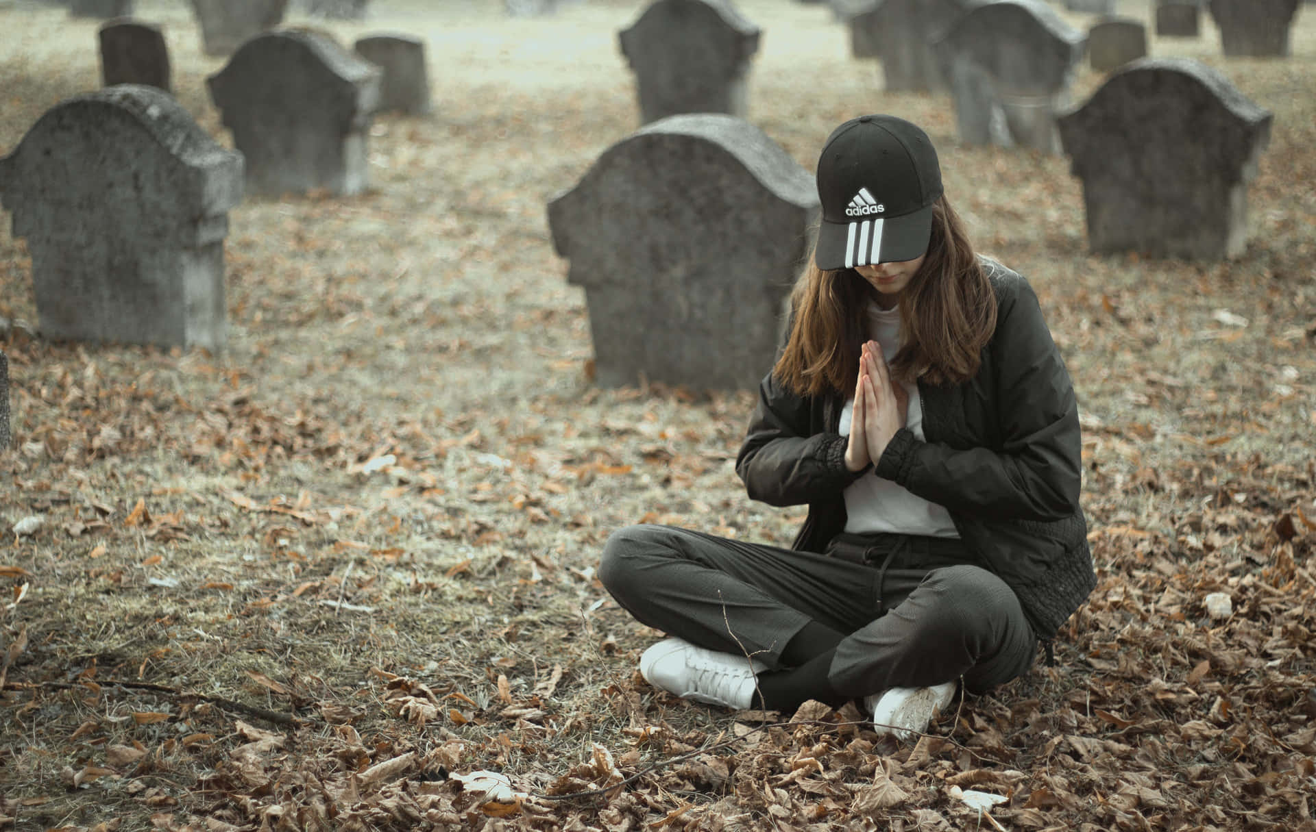 Serene Woman Praying In Cemetery Background