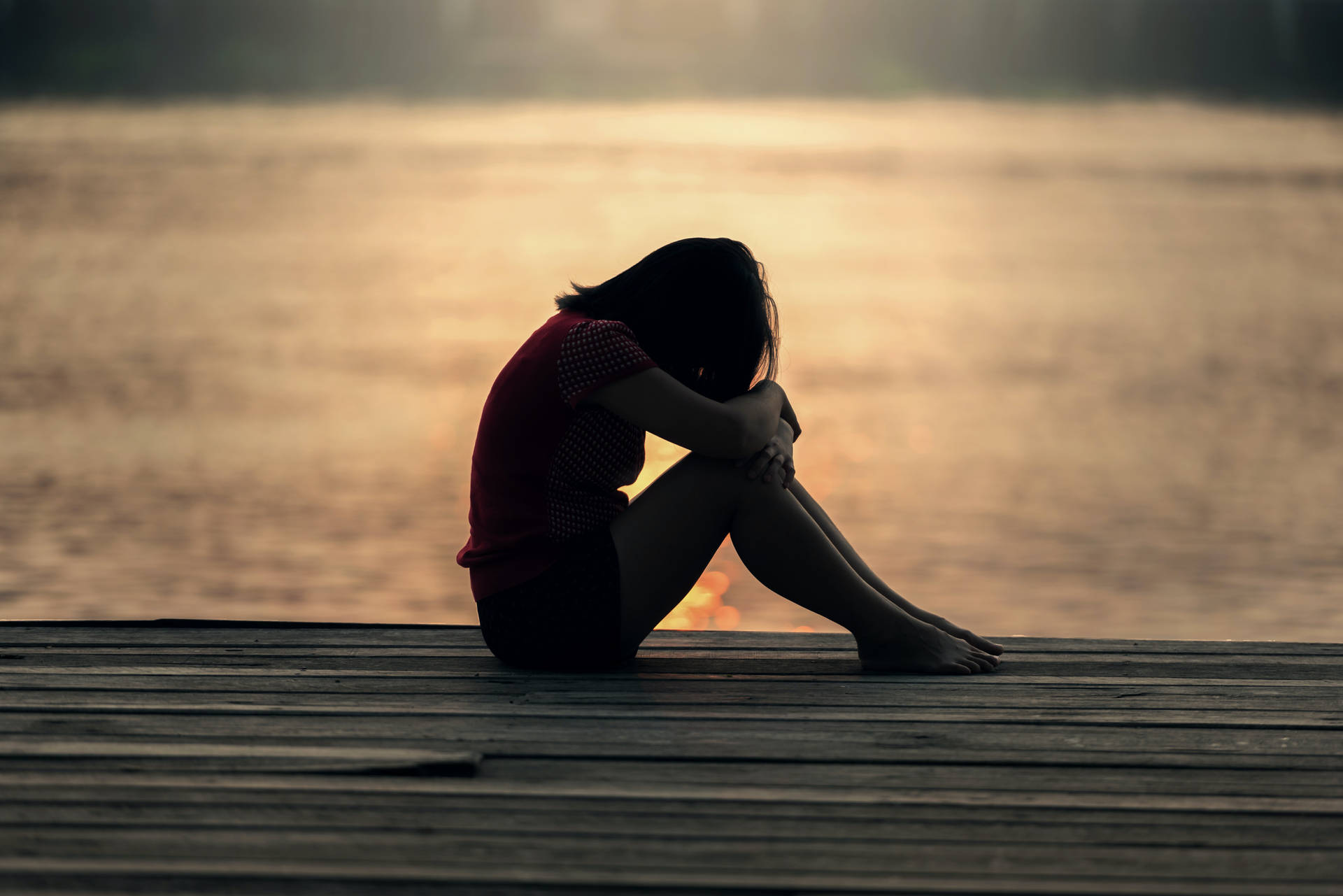 Serenity In Solitude: A Lone Girl Reflecting On A Dock Background