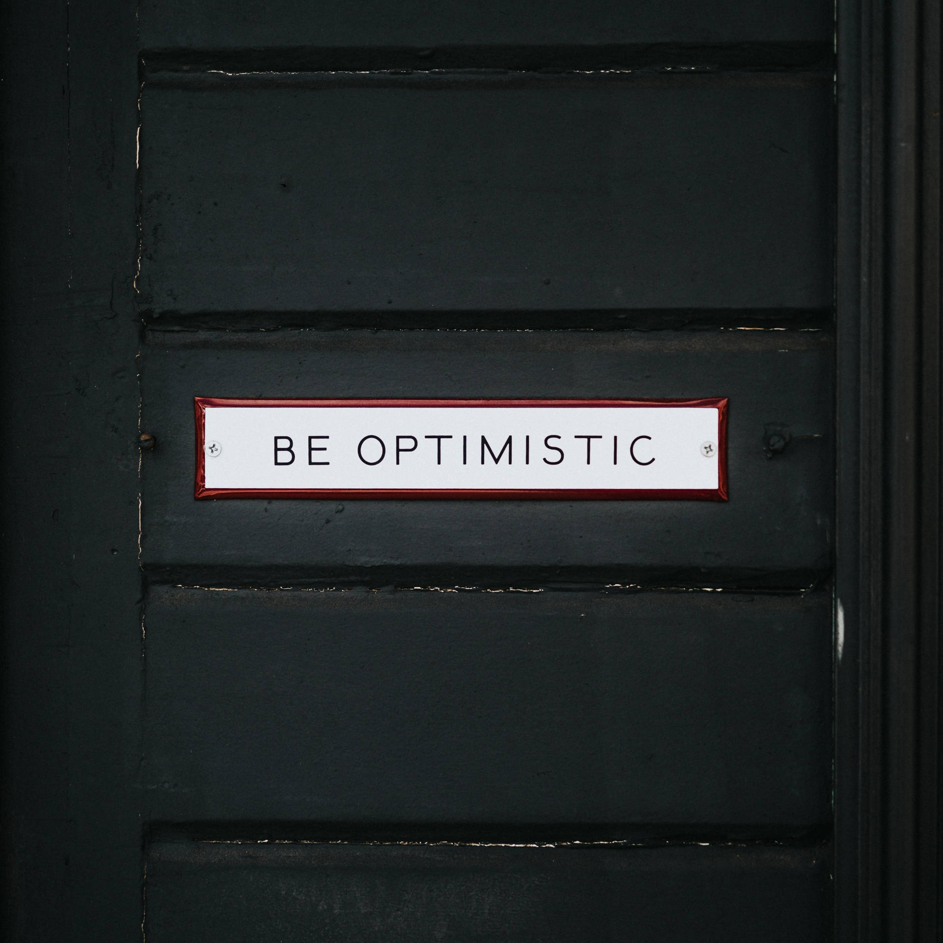 Shining Door Sign Displaying The Word Optimistic