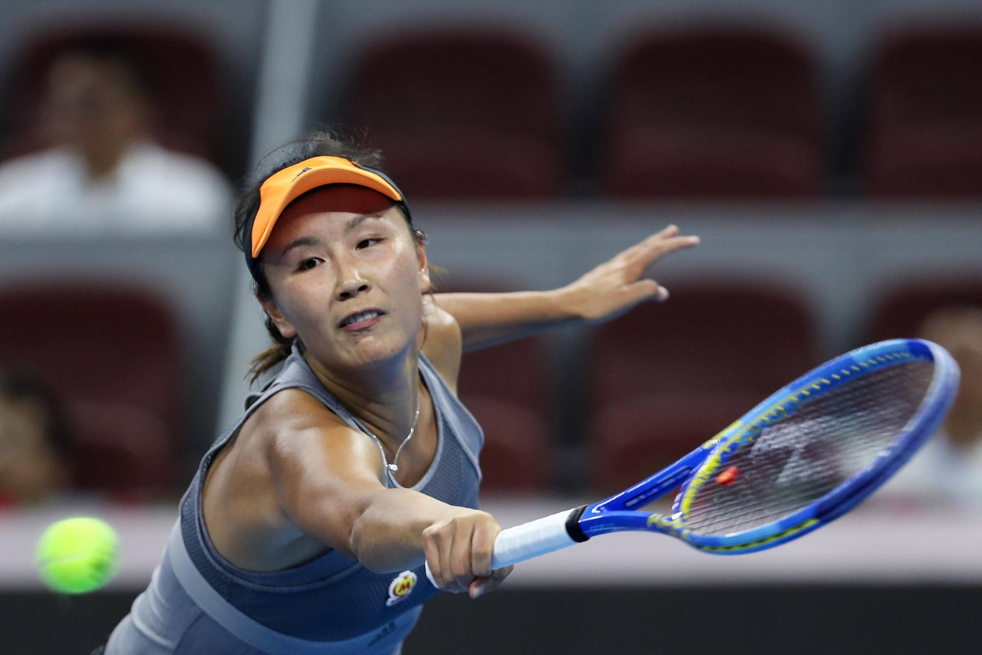 Shuai Peng Powerfully Reaching For A Tennis Ball In A Match Background