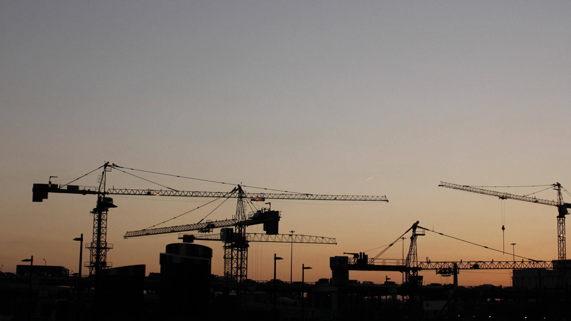 Silhouetted Construction Cranes During Sunset Background