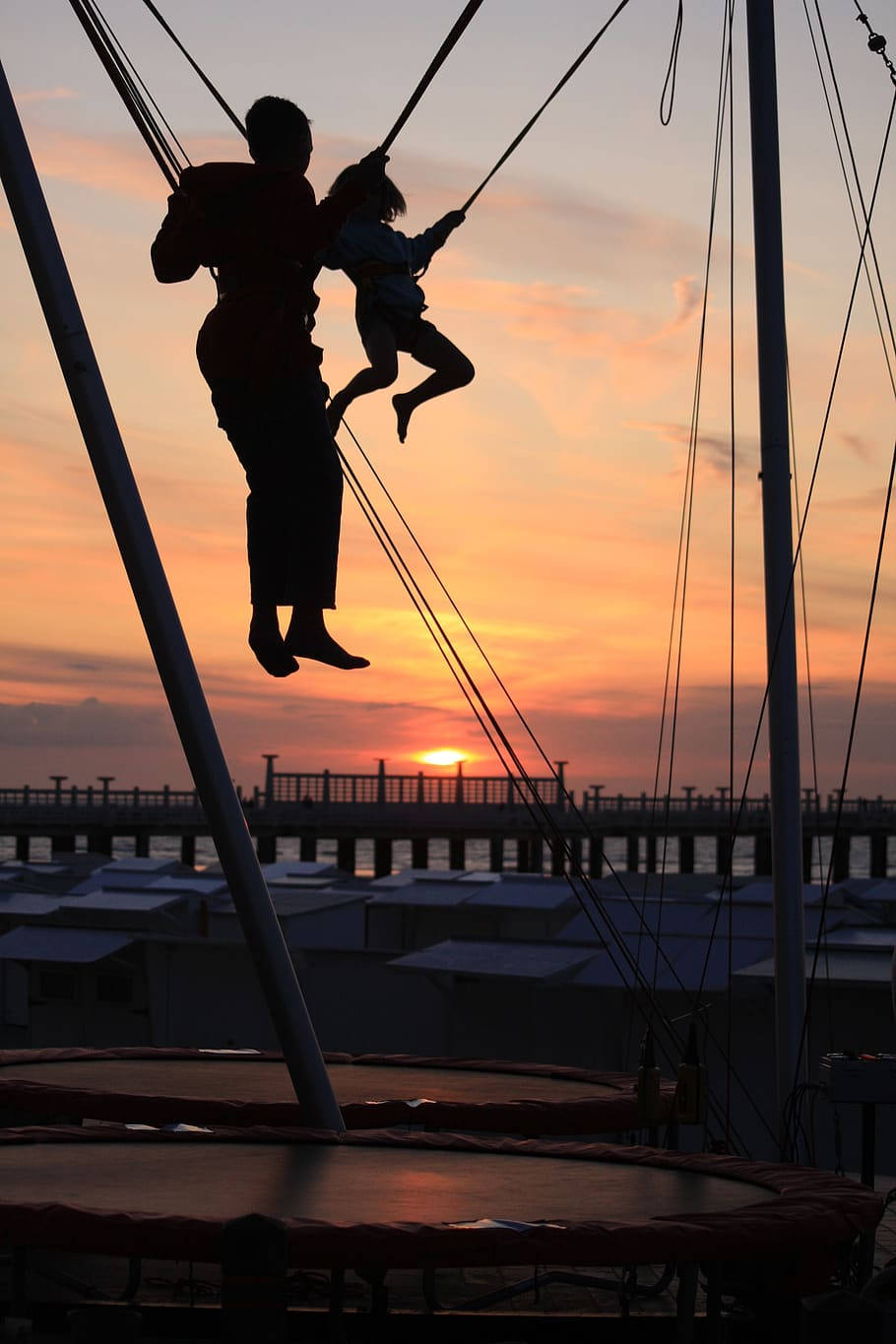 Silhouetted Father And Son Jumping From Trampoline Background