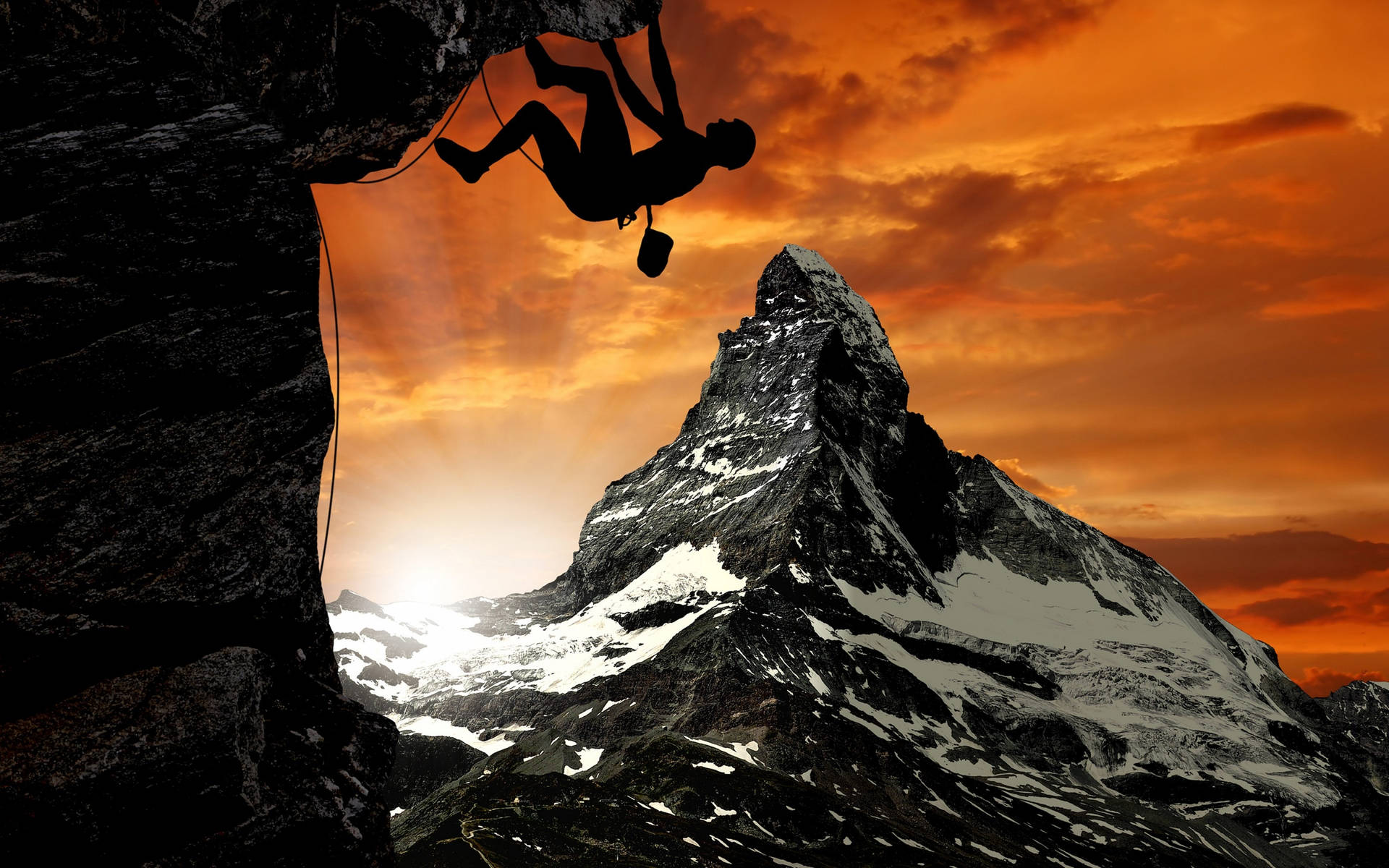 Silhouetted Man Rock Climbing Under Orange Sky Background