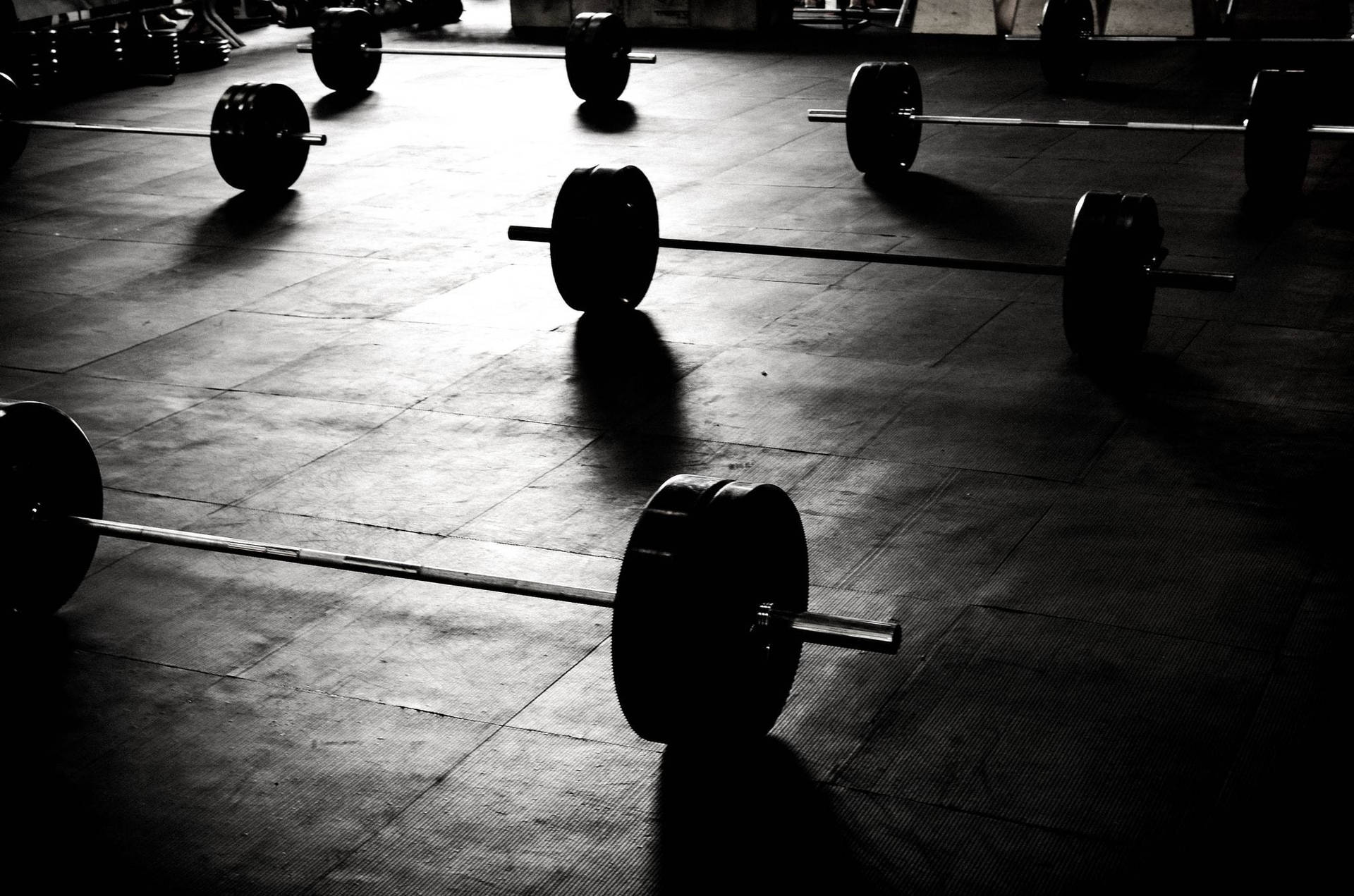 Silhouettes Of Barbells Immersed In Dramatic Lighting Background