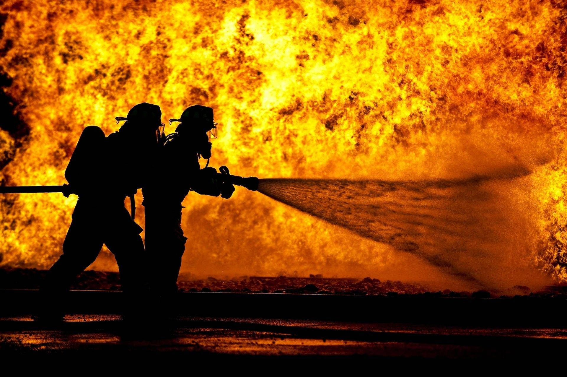 Silhouettes Of Firefighters Putting Out Fire Background