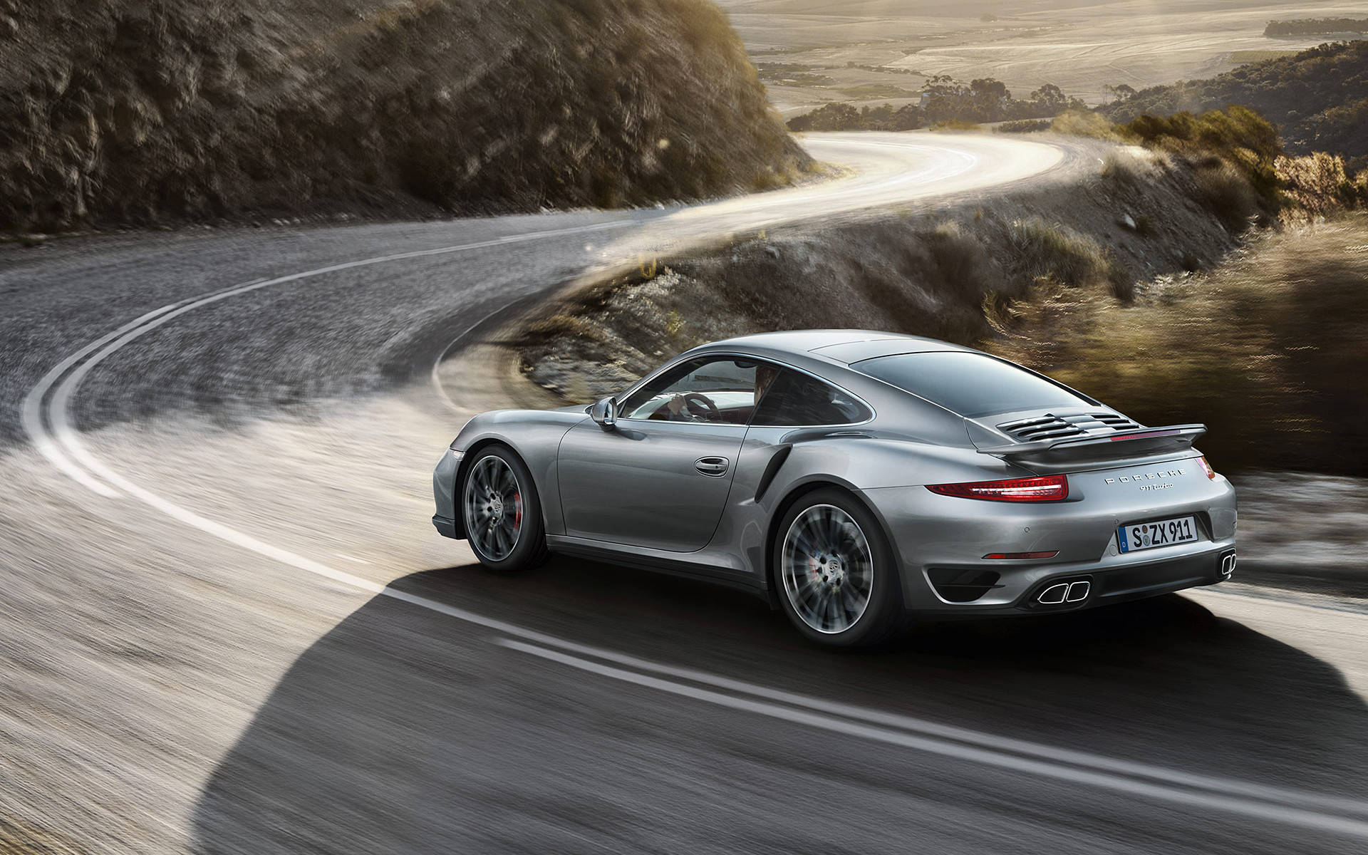 Silver Porsche 911 Racing Down The Road Background