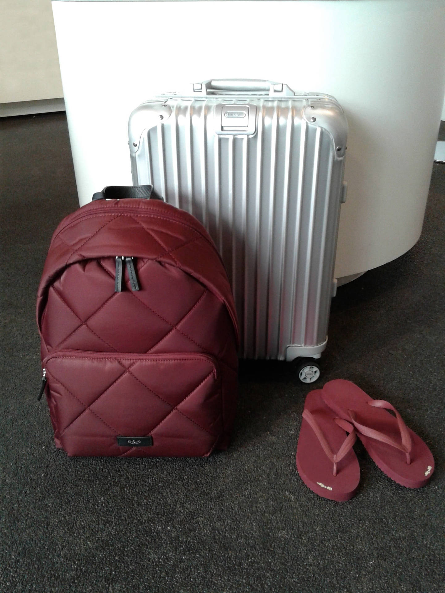 Silver Rimowa Suitcase And Maroon Bag