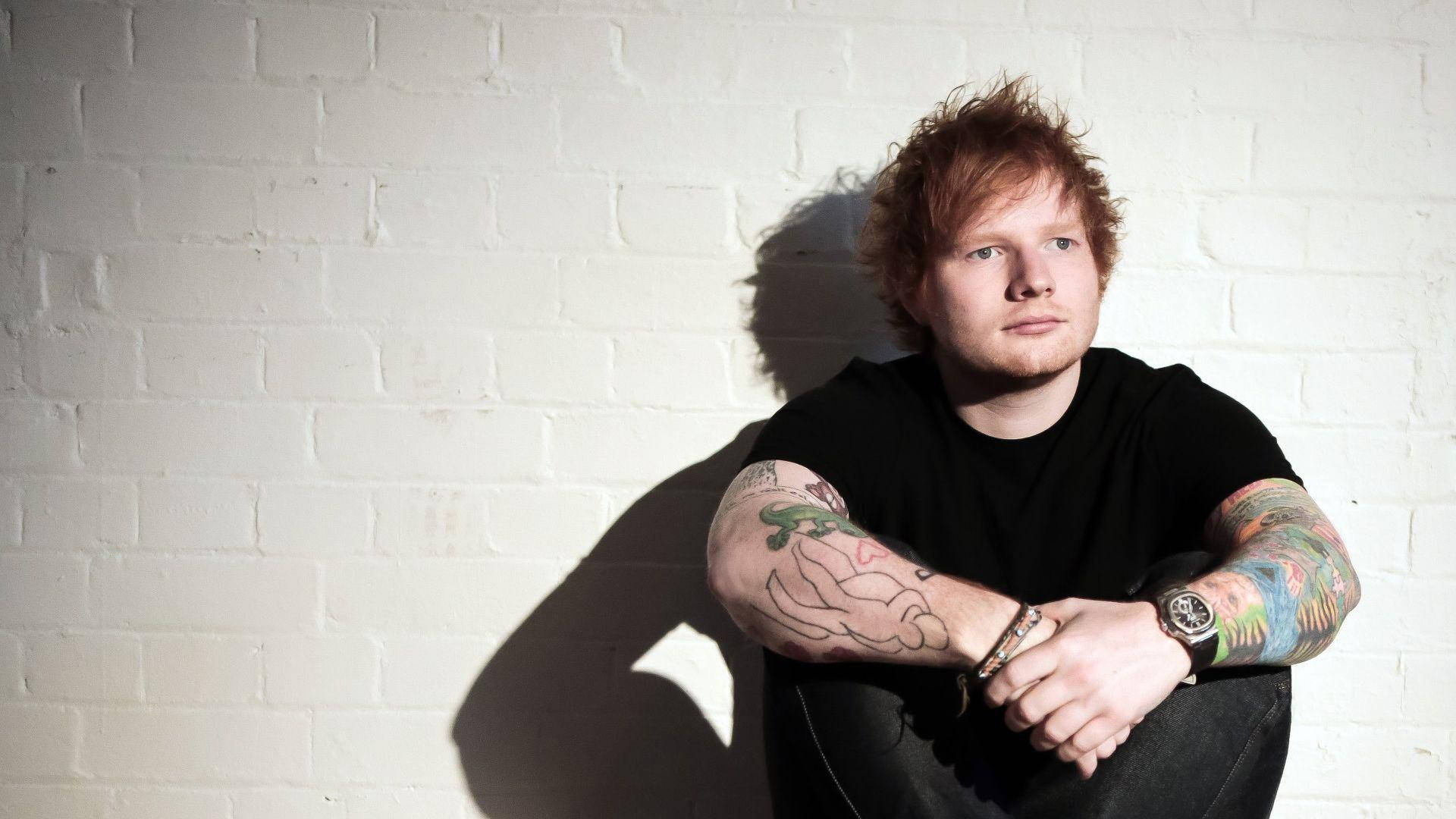 Singer-songwriter Ed Sheeran Posing In A Charming Fashion Background