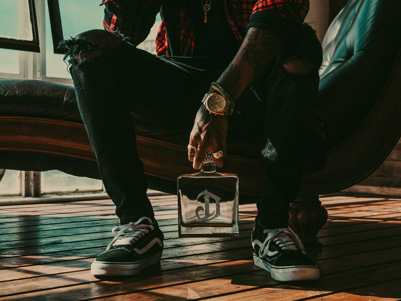 Sitting Man Holding A Deleón Tequila Bottle