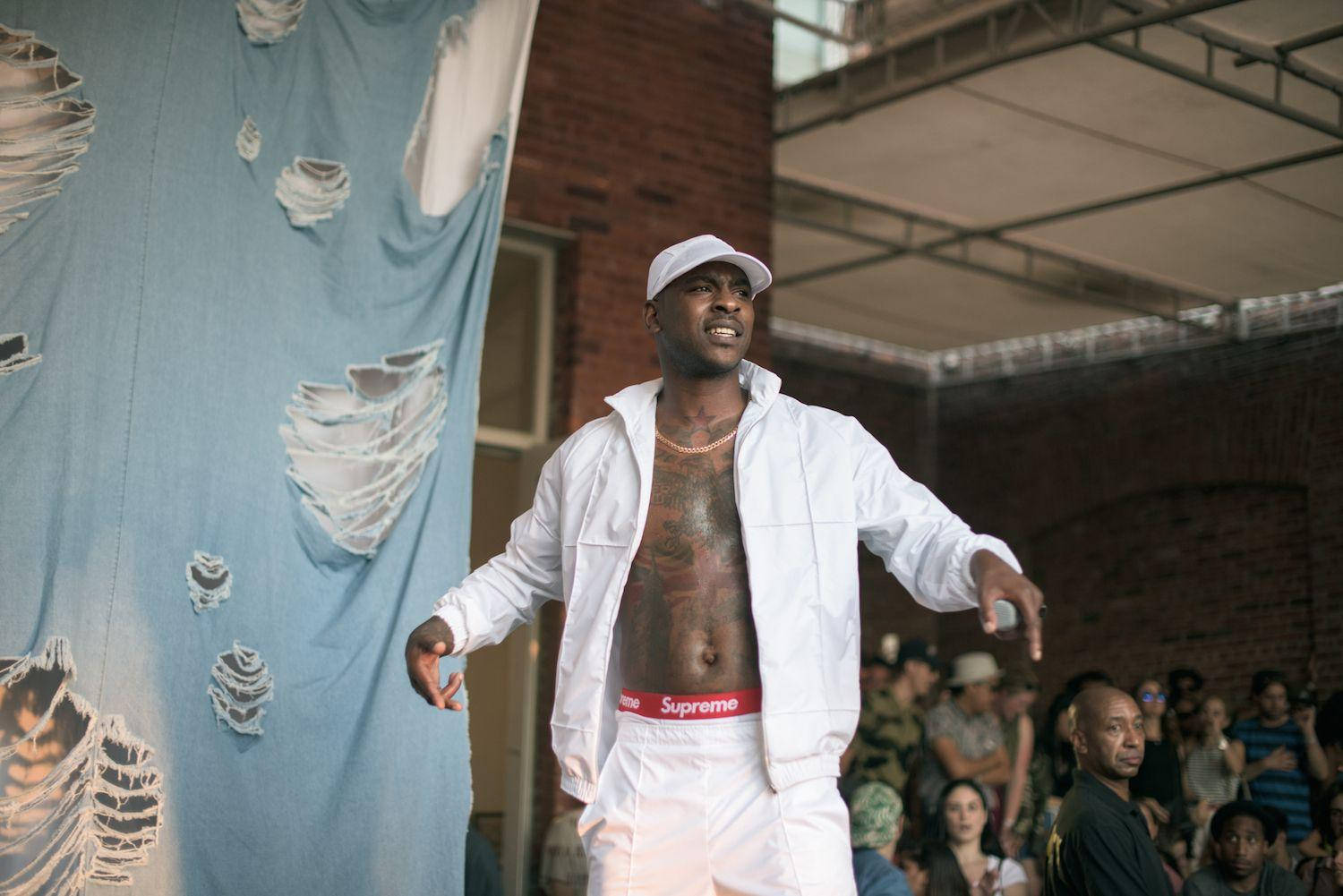 Skepta Wearing A White Jacket Background