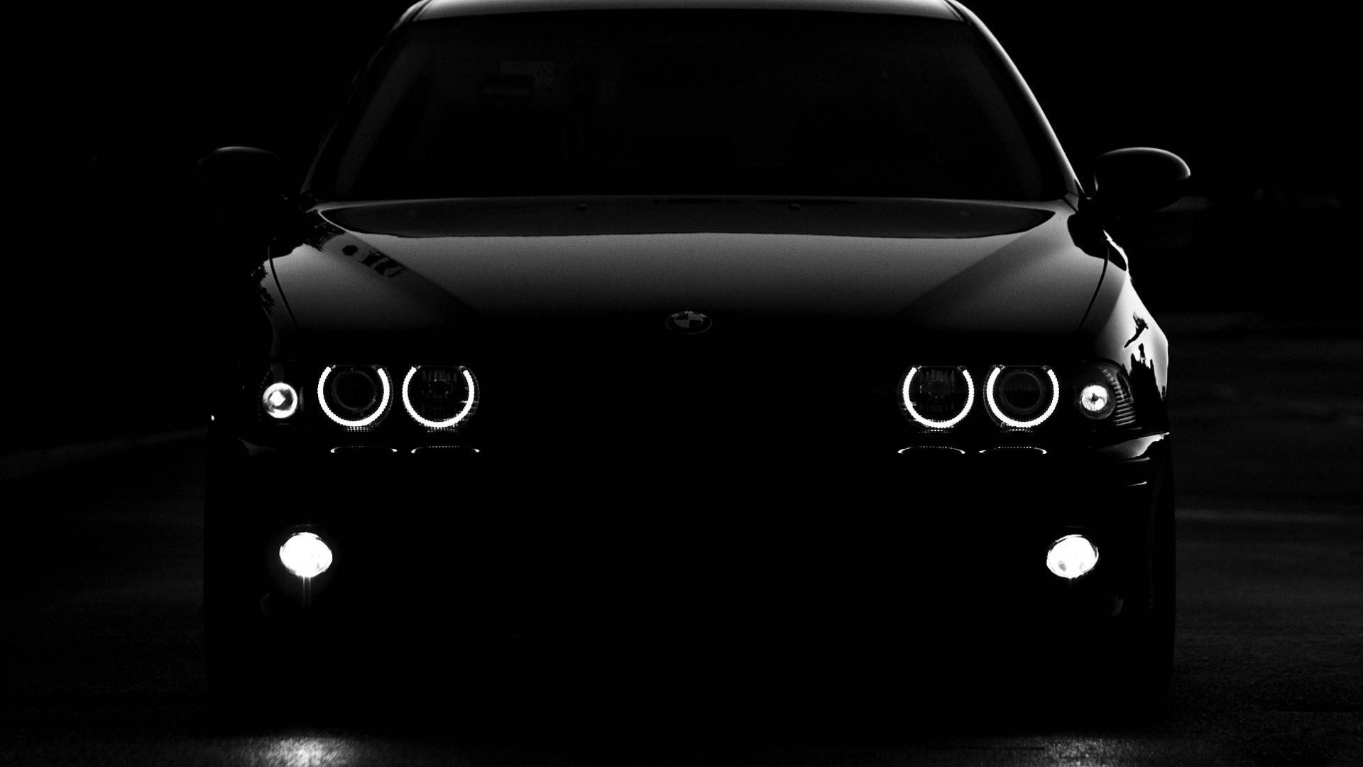 Sleek Black Bmw Car In Night City Scenery Background
