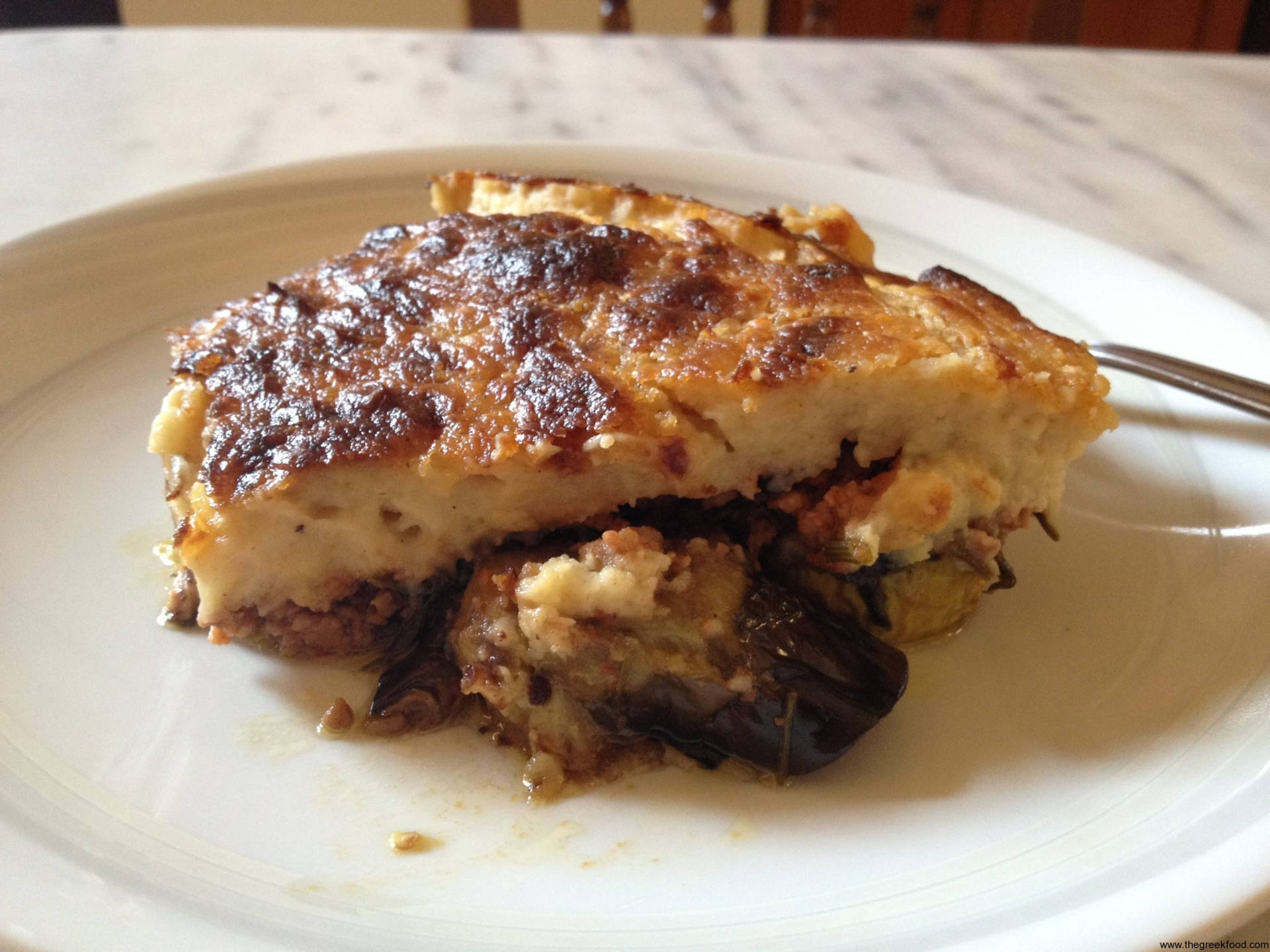 Slice Of Baked Moussaka On A White Ceramic Background