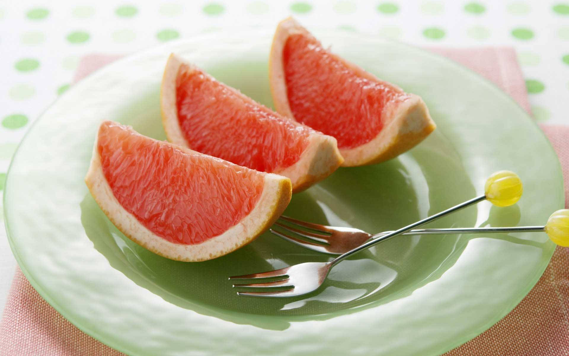 Sliced Grapefruits On A Plate With Forks Background